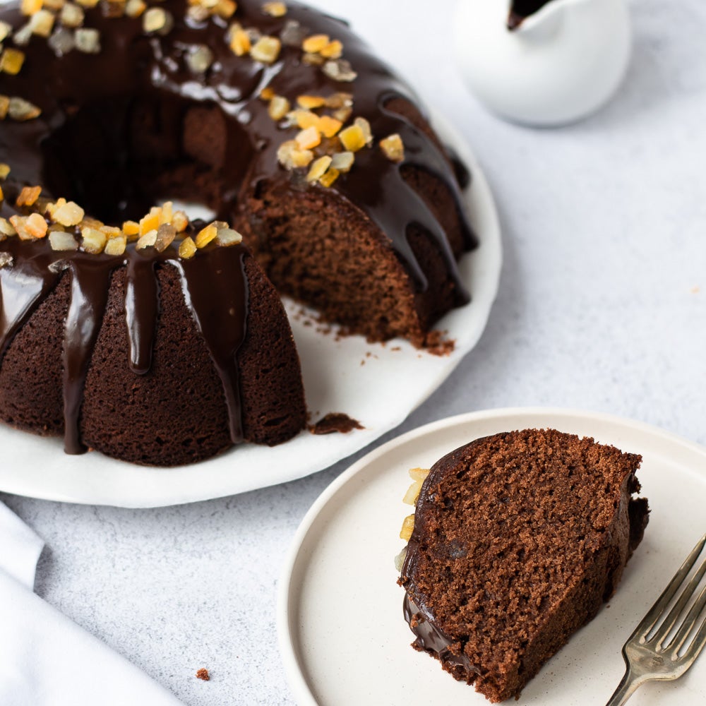 chocolate orange bundt cake on plate with chocolate drizzle on top with candid orange peel