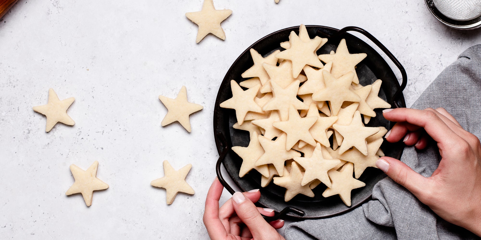 A top down view of a hand taking from some star shaped vegan biscuits in a bowl