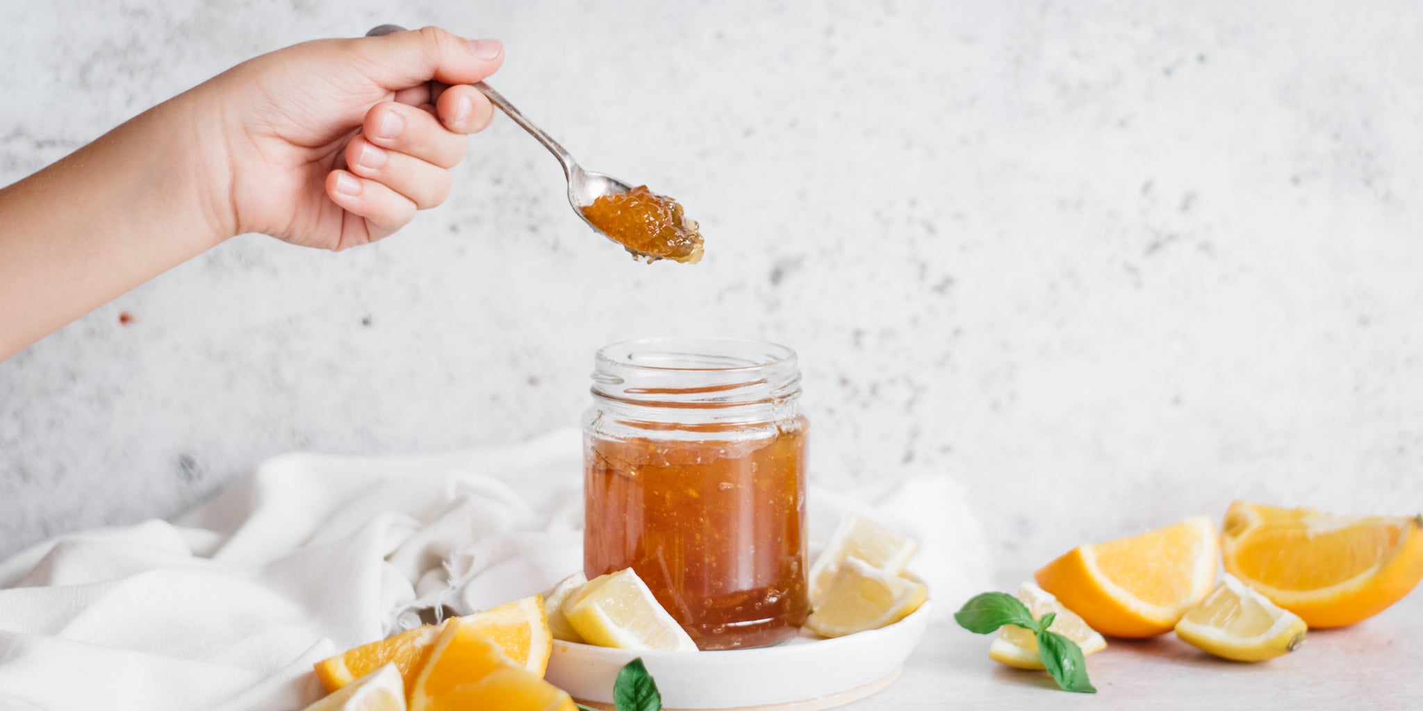 Jar of marmalade with a hand spooning out a spoonful