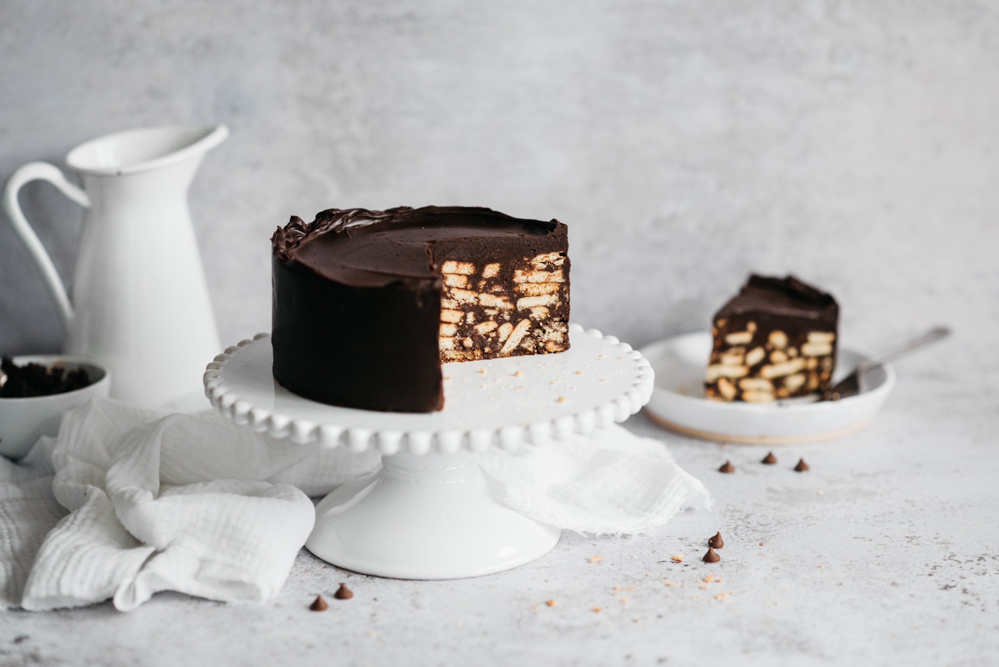 Chocolate Biscuit Cake on a cake stand showing the biscuit inside with chocolate ganache coating