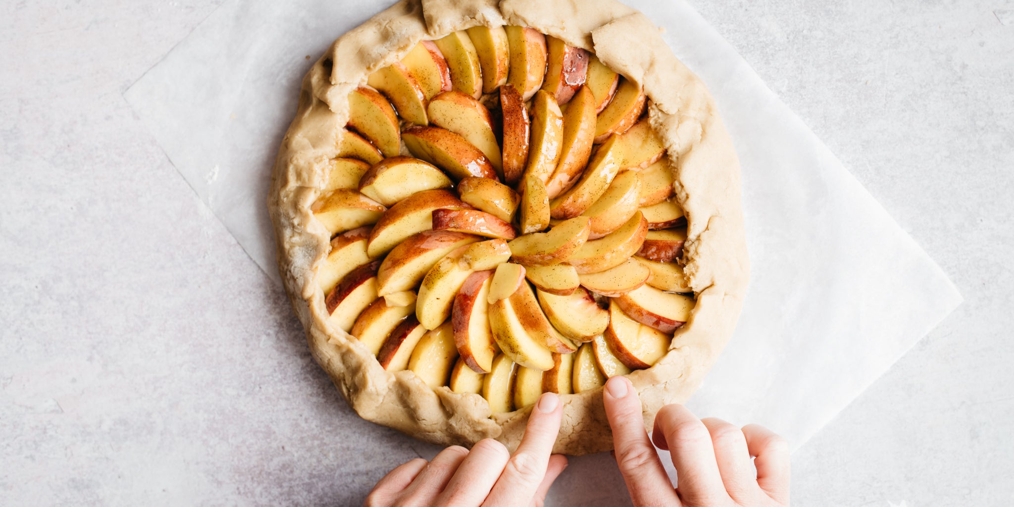 Hand pinching the pastry in place on galette