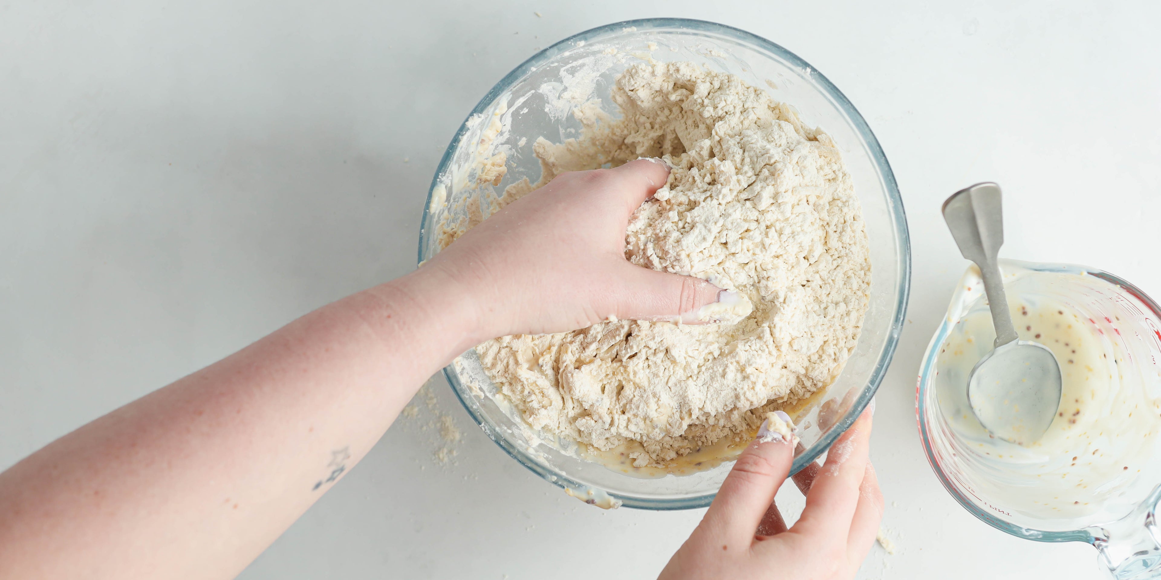 Top view of Cheese Scone dough being mixed and combined with hands crumbling the dough