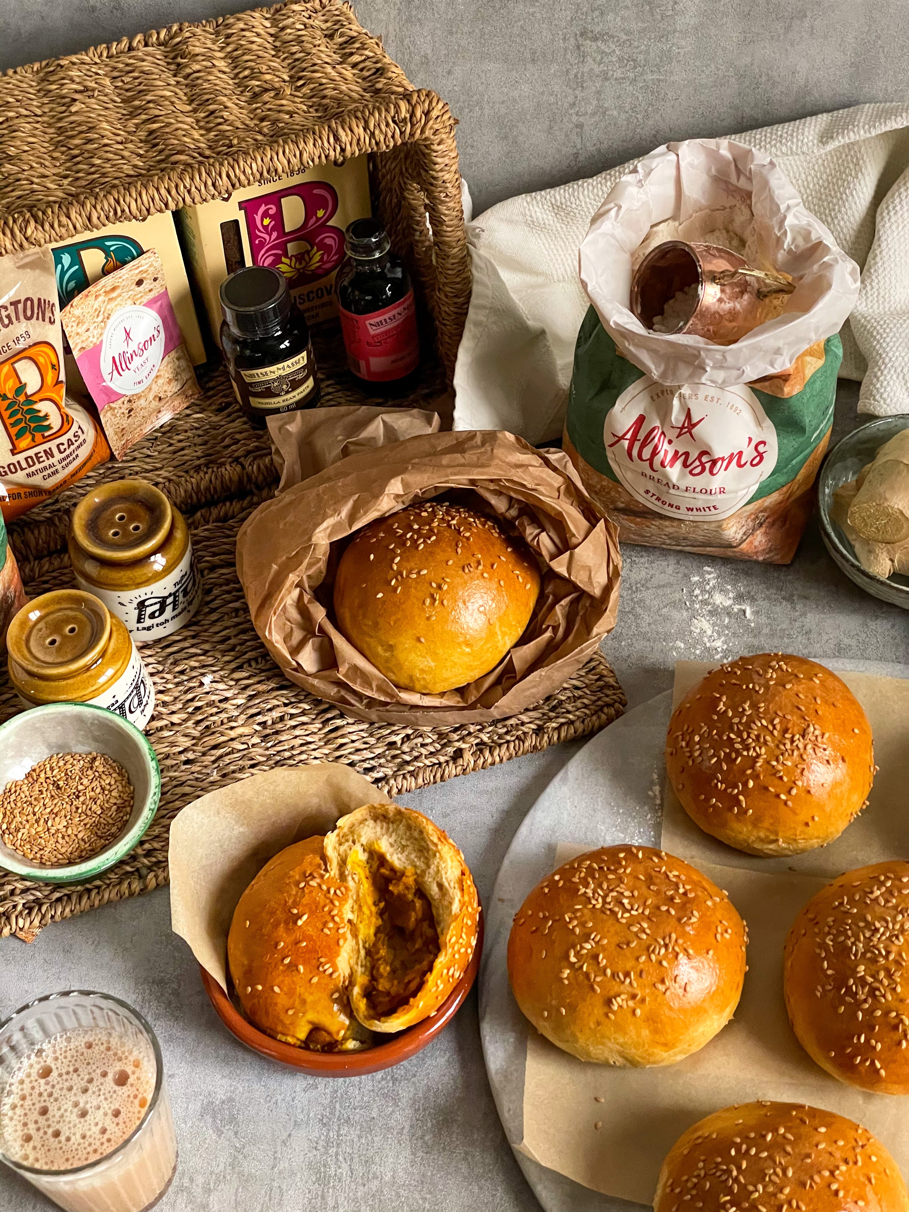 Top down view of spiced masala buns next to a hamper filled with baking ingredients
