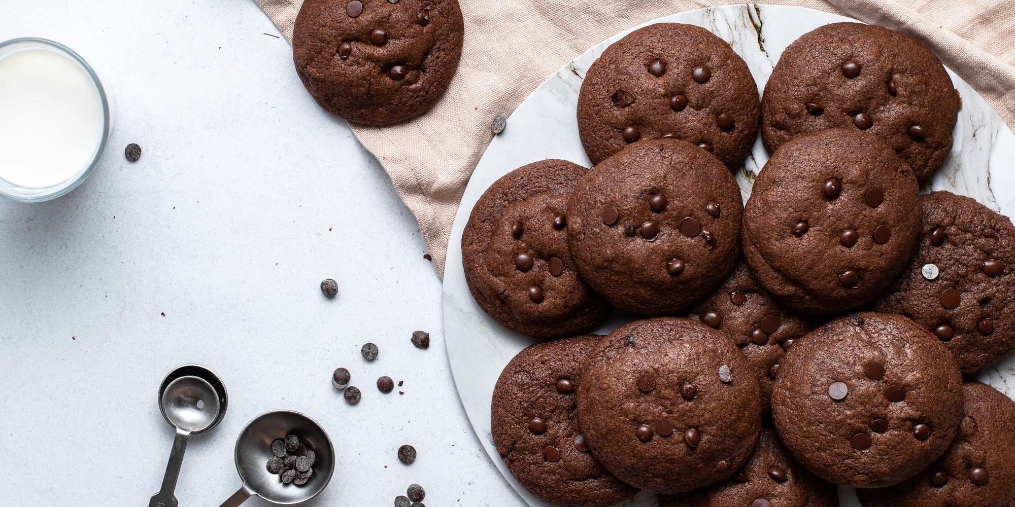Chocolate & Peanut Butter Stuffed Cookies with measuring spoons and sprinkles of chocolate chips