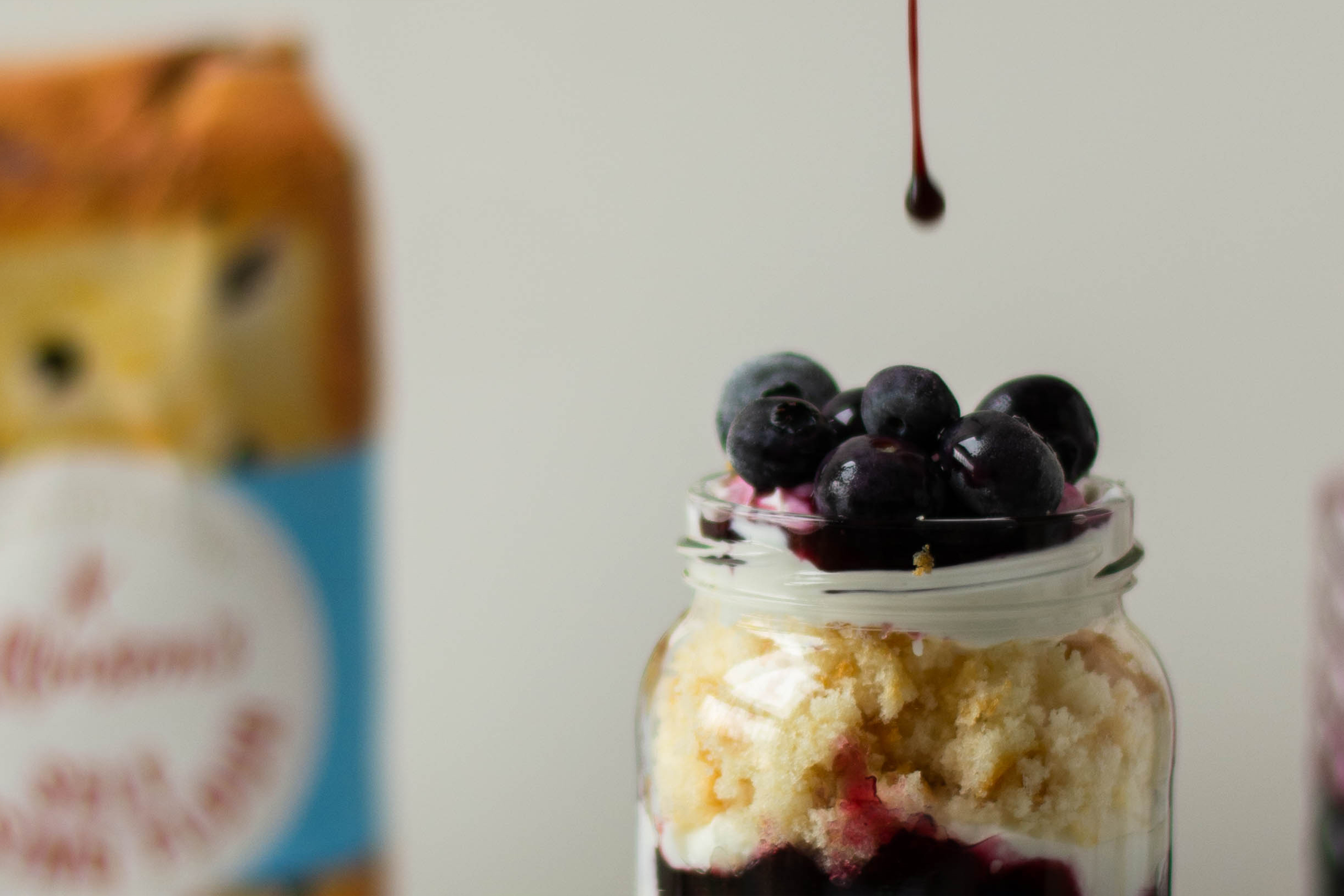 Top view of a Lemon & Blueberry Cake Jar with a dollop of Blueberry jam about the fall onto the top of the Lemon & Blueberry Cake Jar