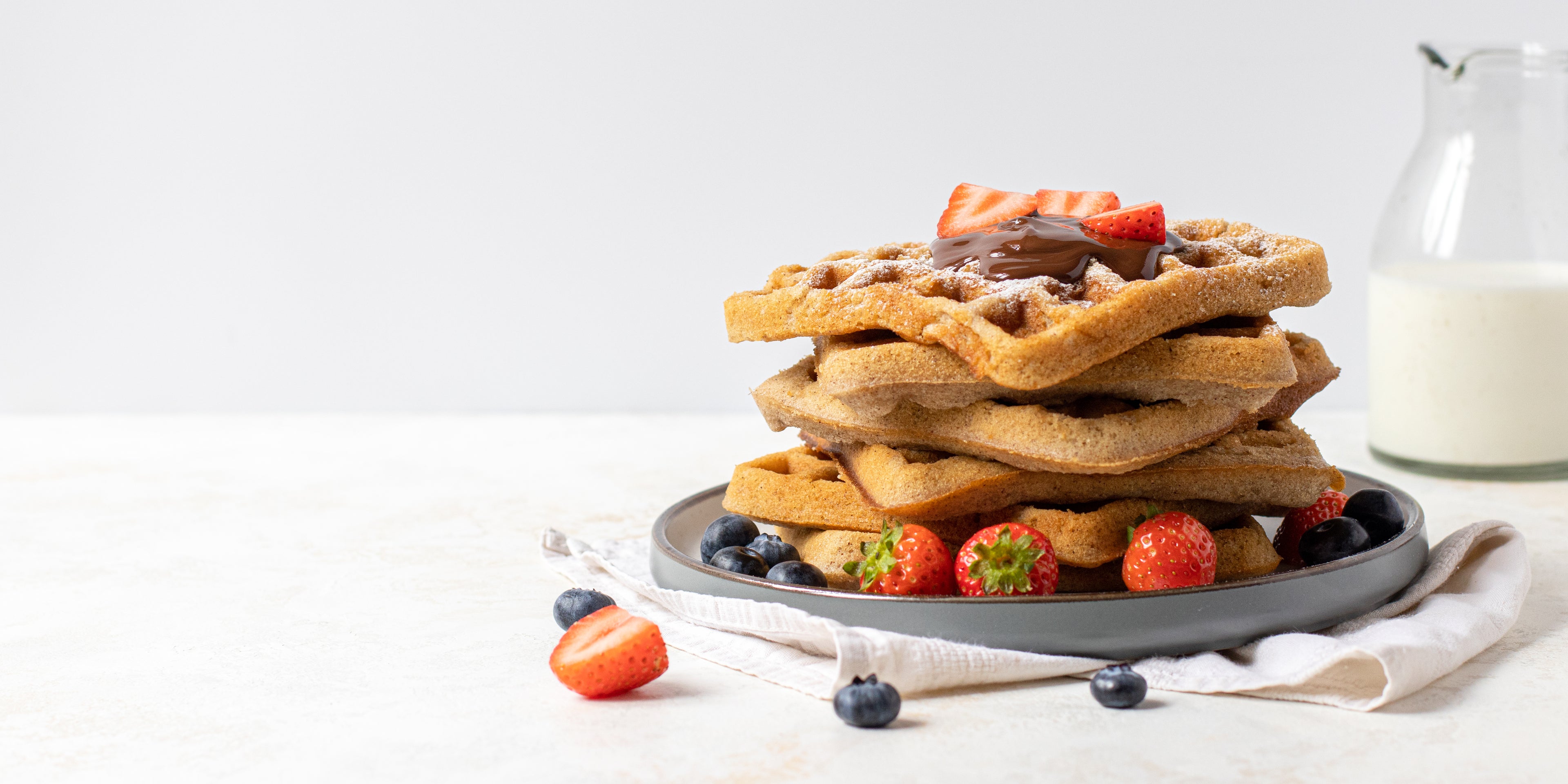 Stack of Waffles topped with berries, chocolate sauce and dusted with icing sugar