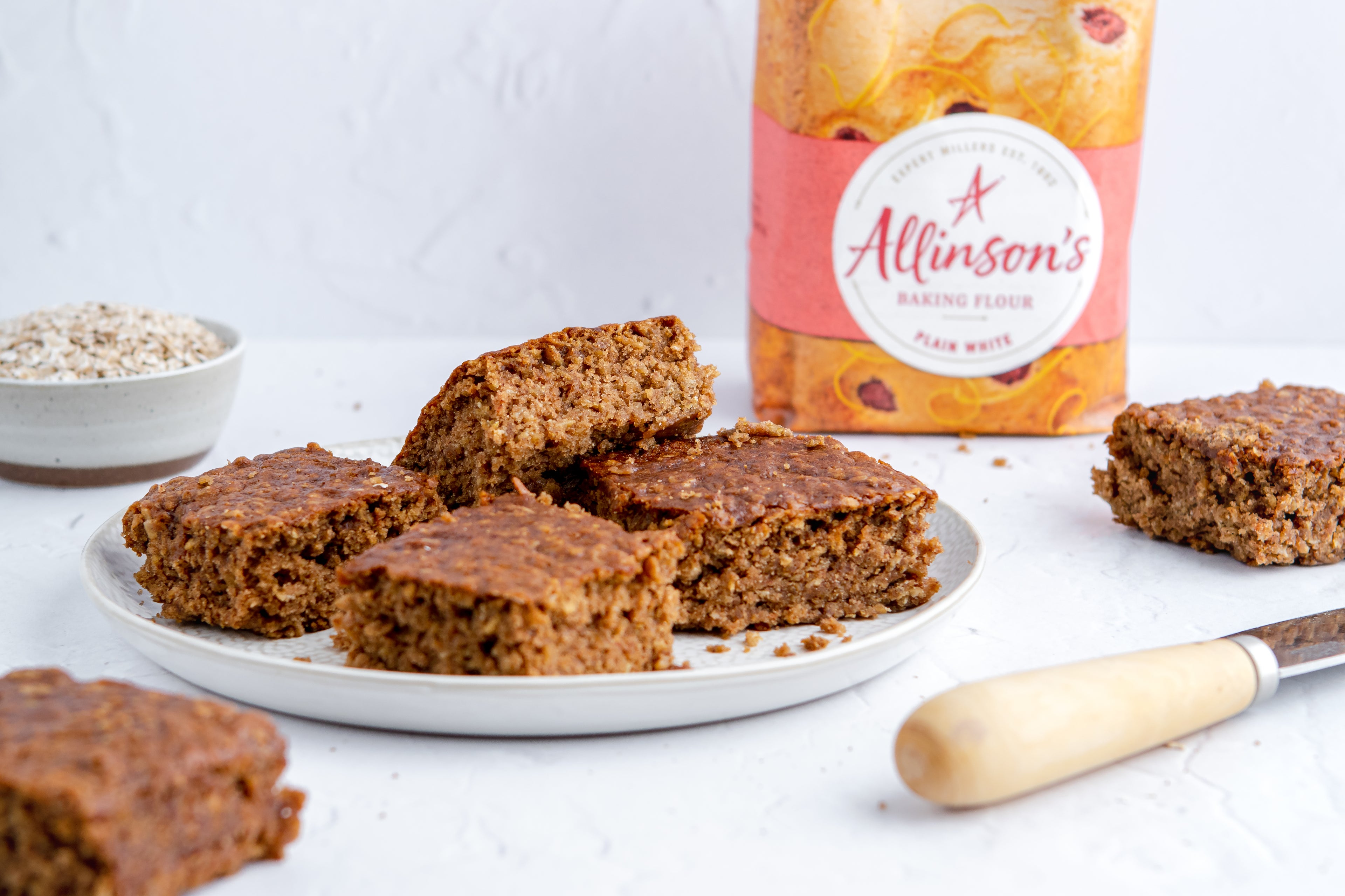Sticky Yorkshire Parkin slices on a plate with Allinson's Plain White flour in the backgroun