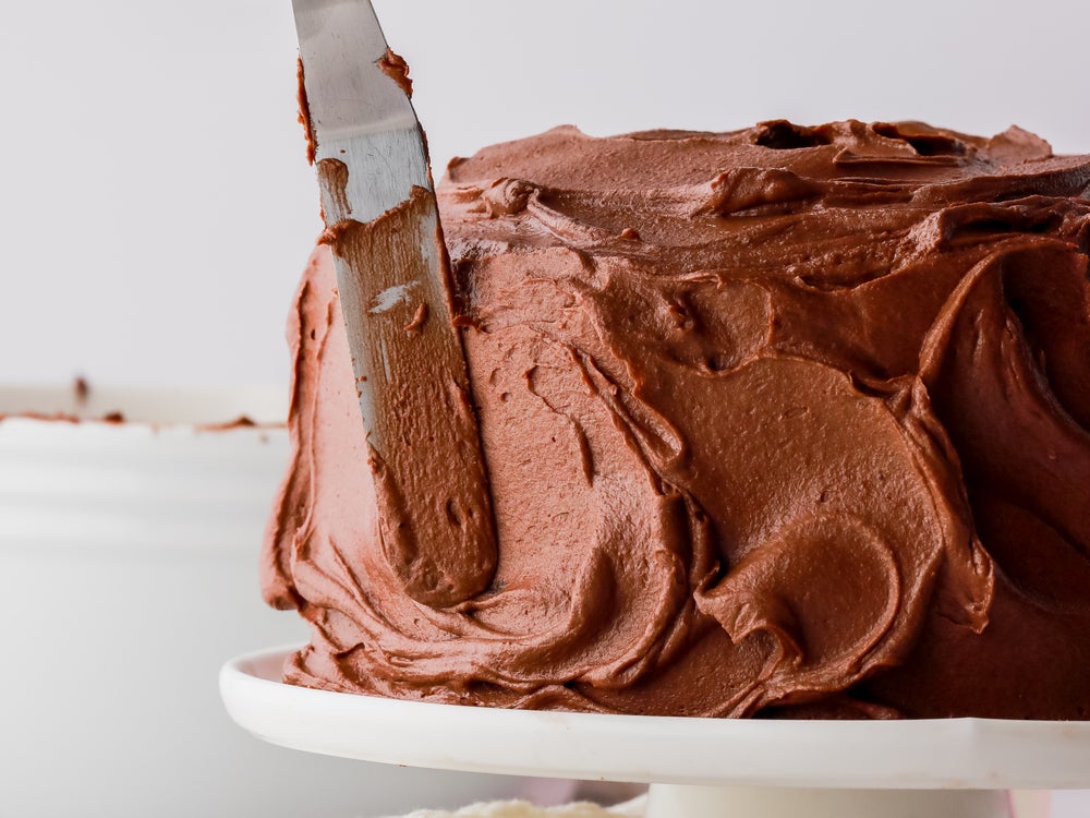 Close up of a cake being smoothed with buttercream icing