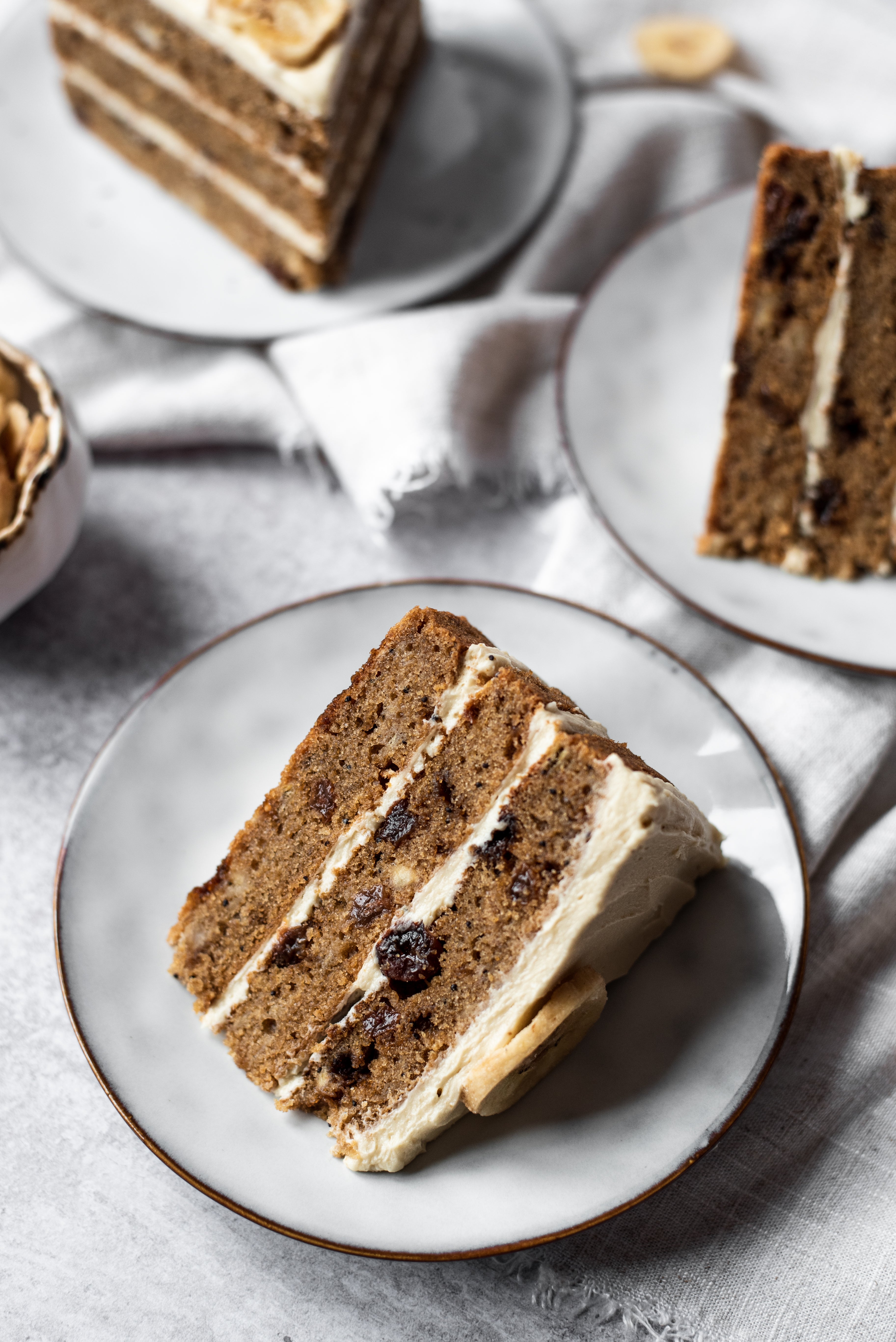 Close up of banana layer cake on plate with buttercream and dried fruit