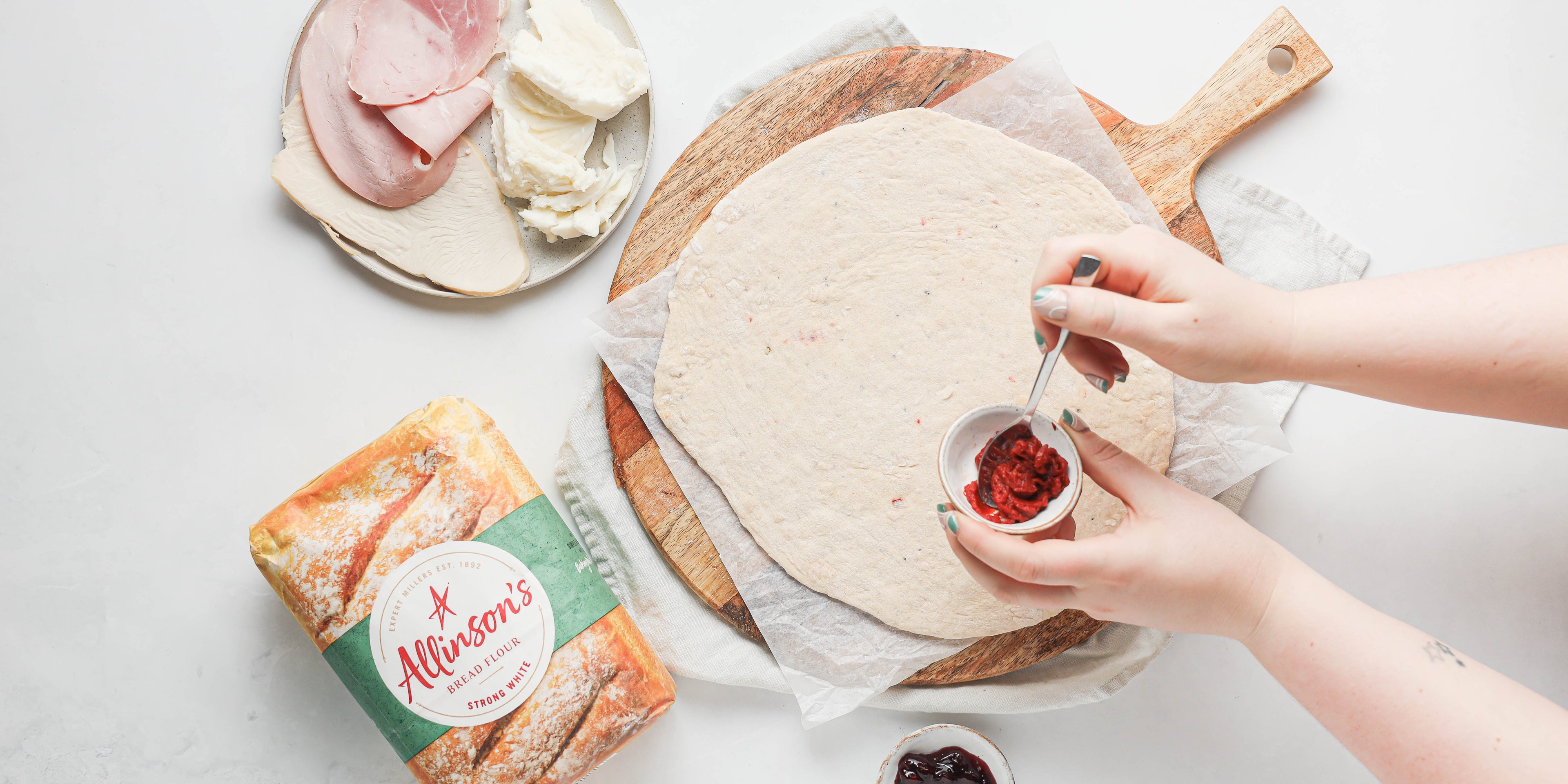 Adding tomato puree to a pizza base