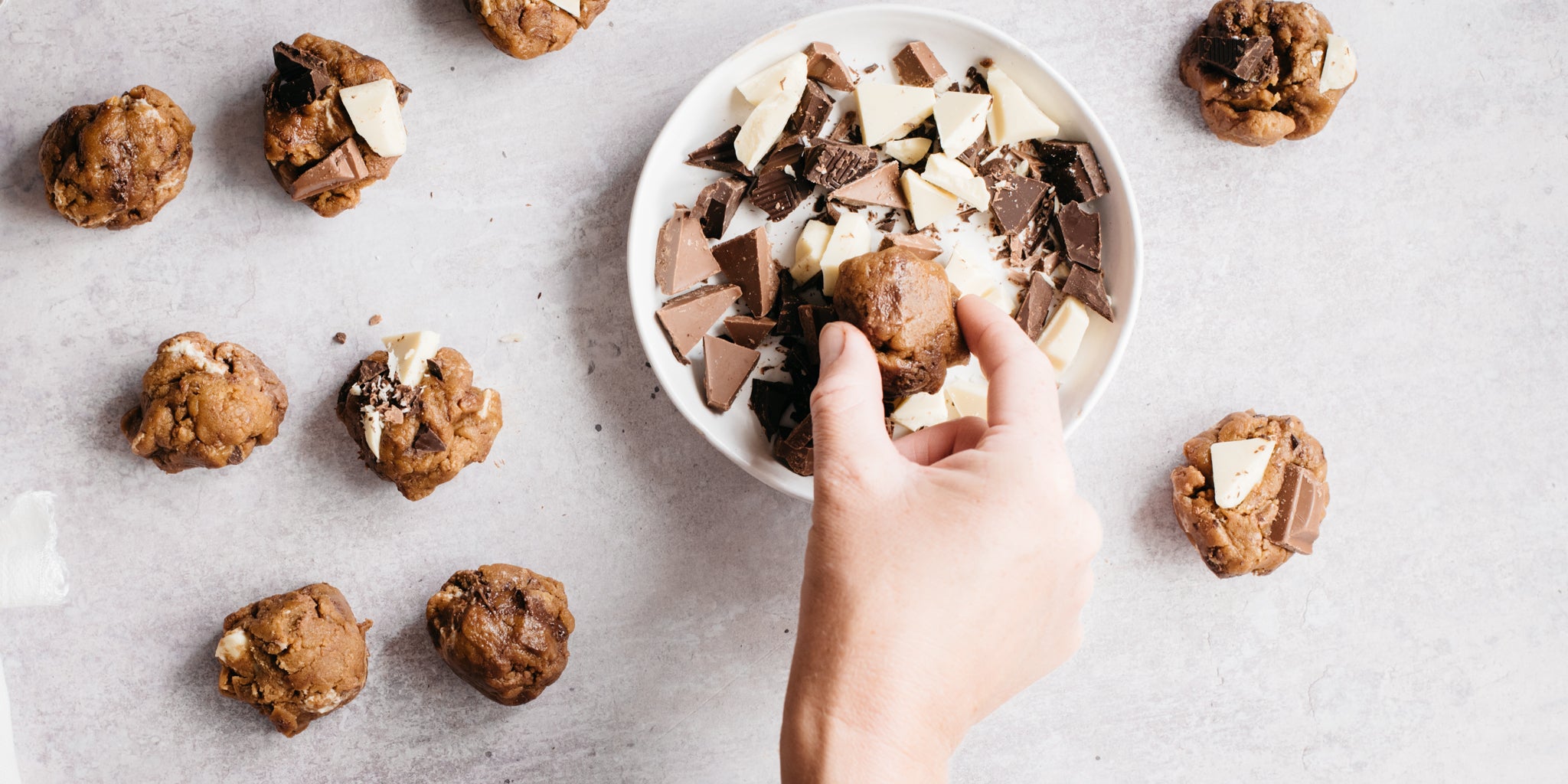 Balls of cookie dough being rolled in chocolate