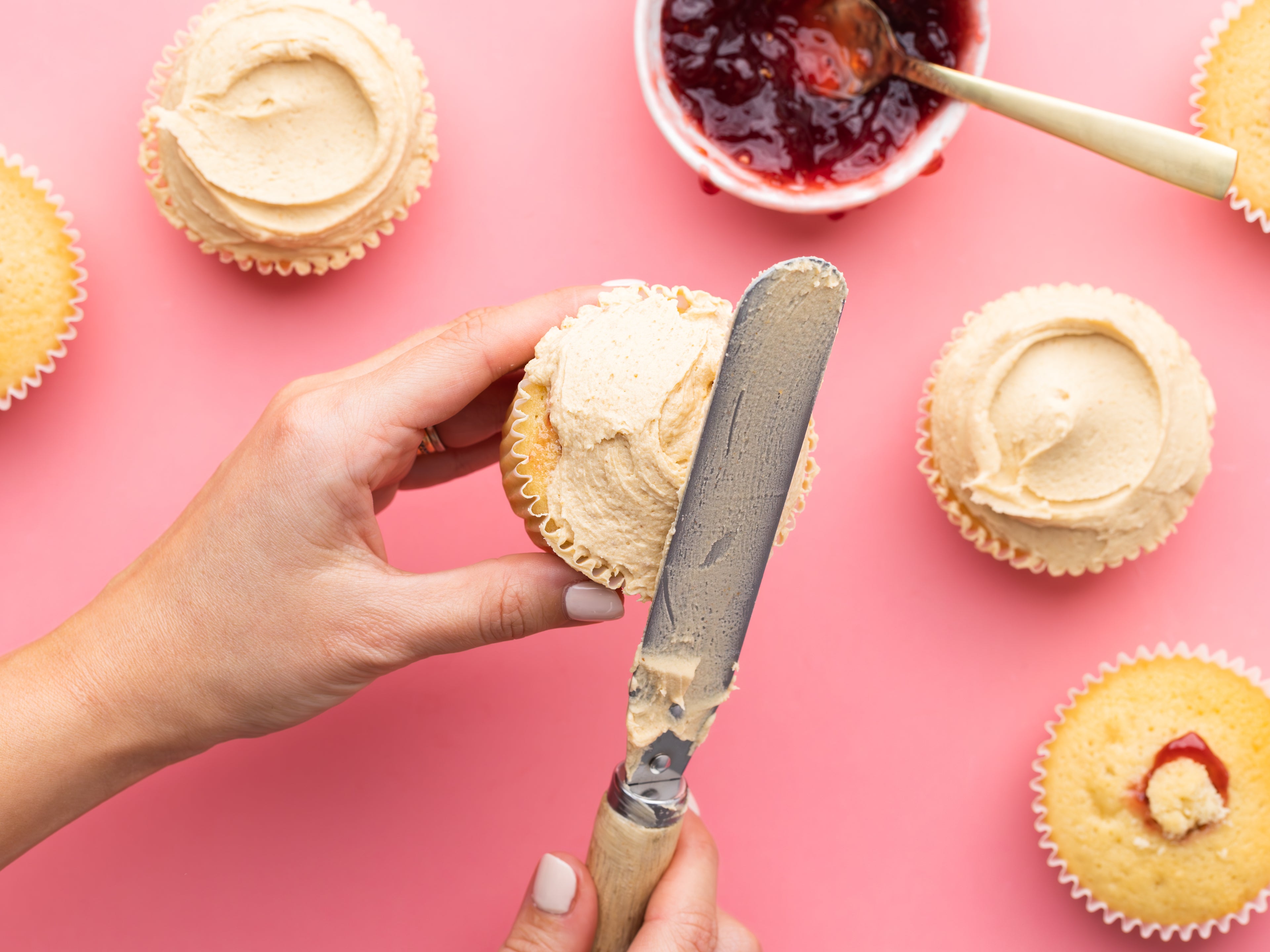 Peanut buttercream being spread on cupcake with spatula