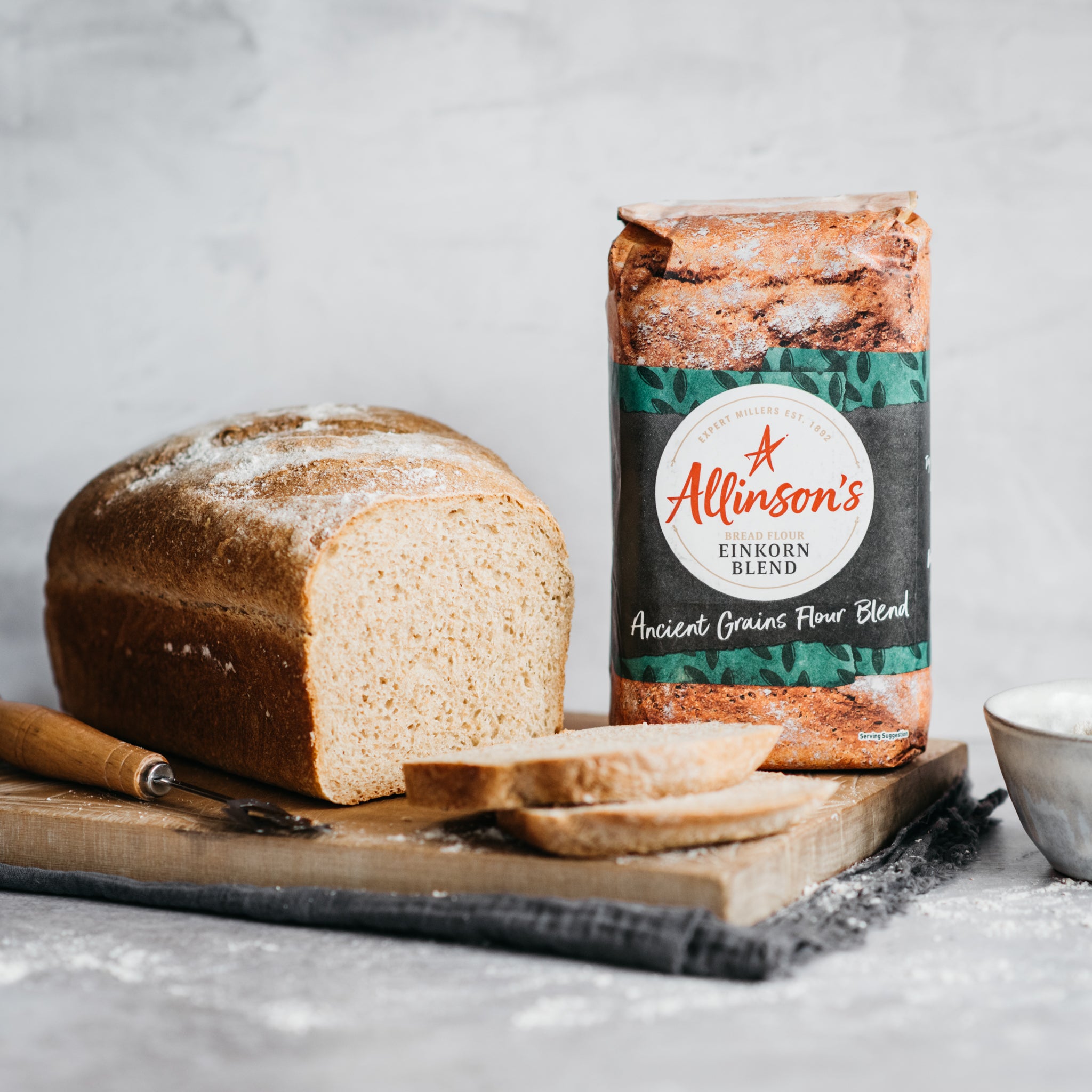 Loaf of bread with two slices in front and bread flour pack