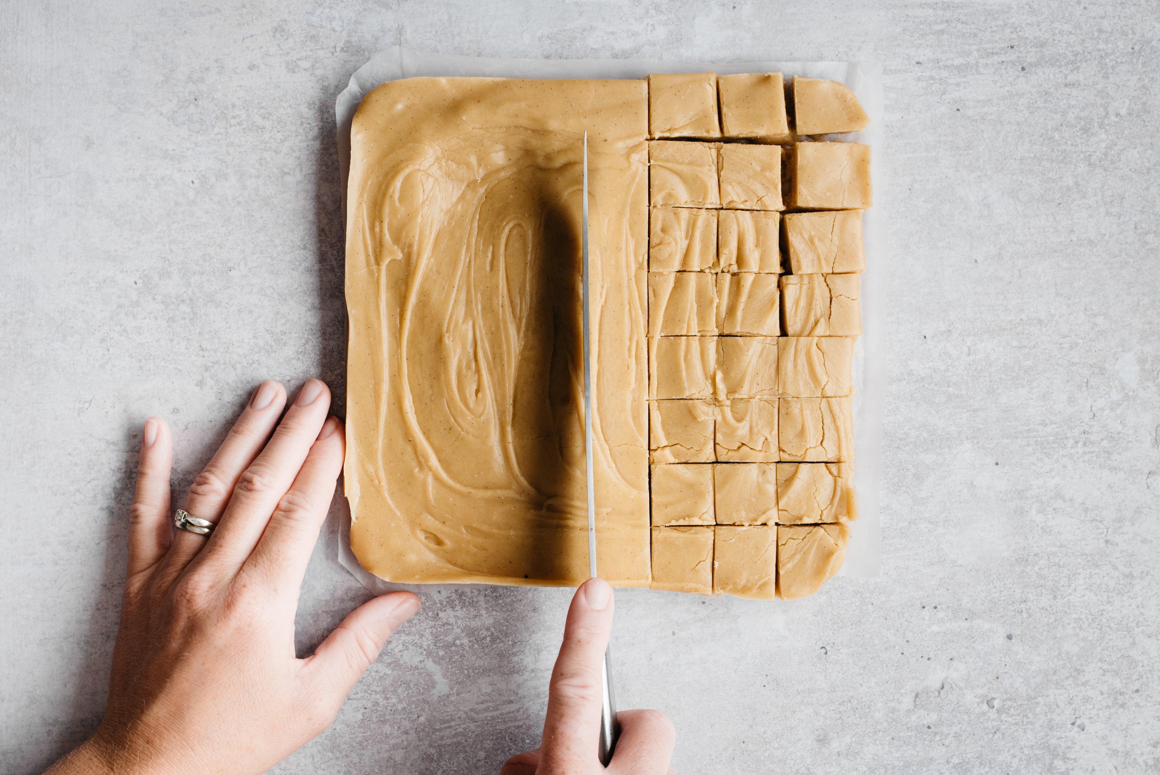 Hand cutting a slab of fudge into cubes with a knife