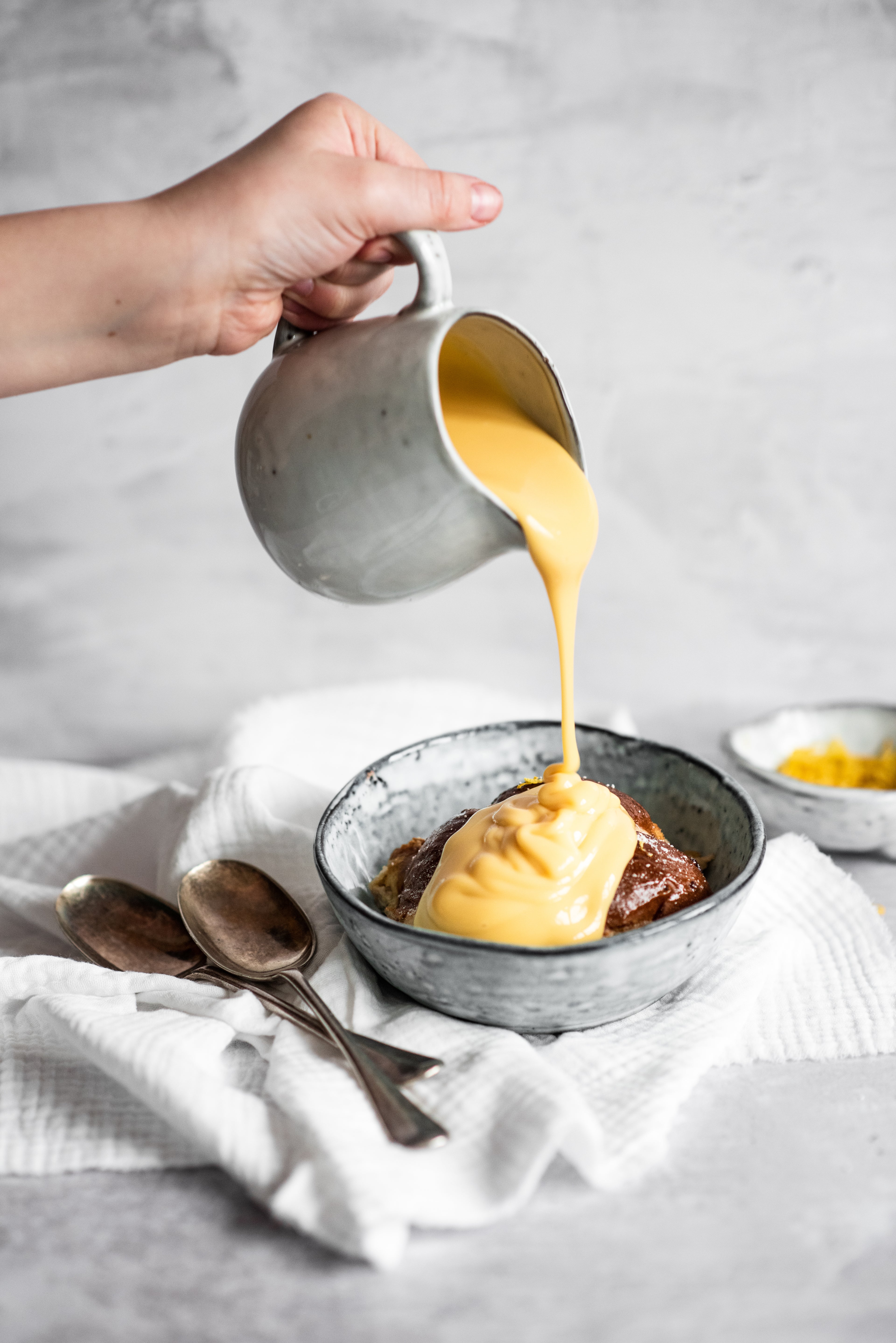 One Hot Cross Bun Bread Butter Pudding with person pouring custard on top