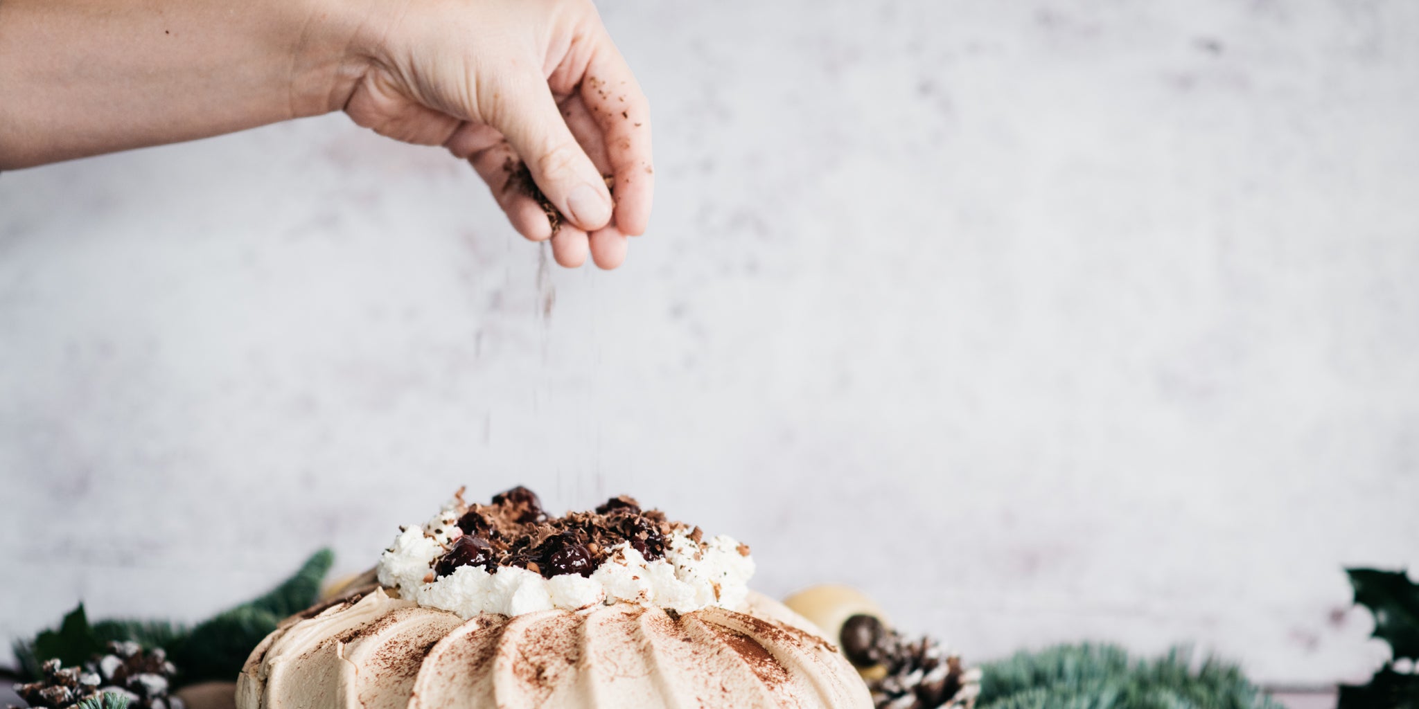 Black Forest Pavlova being hand dusted with chocolate shavings