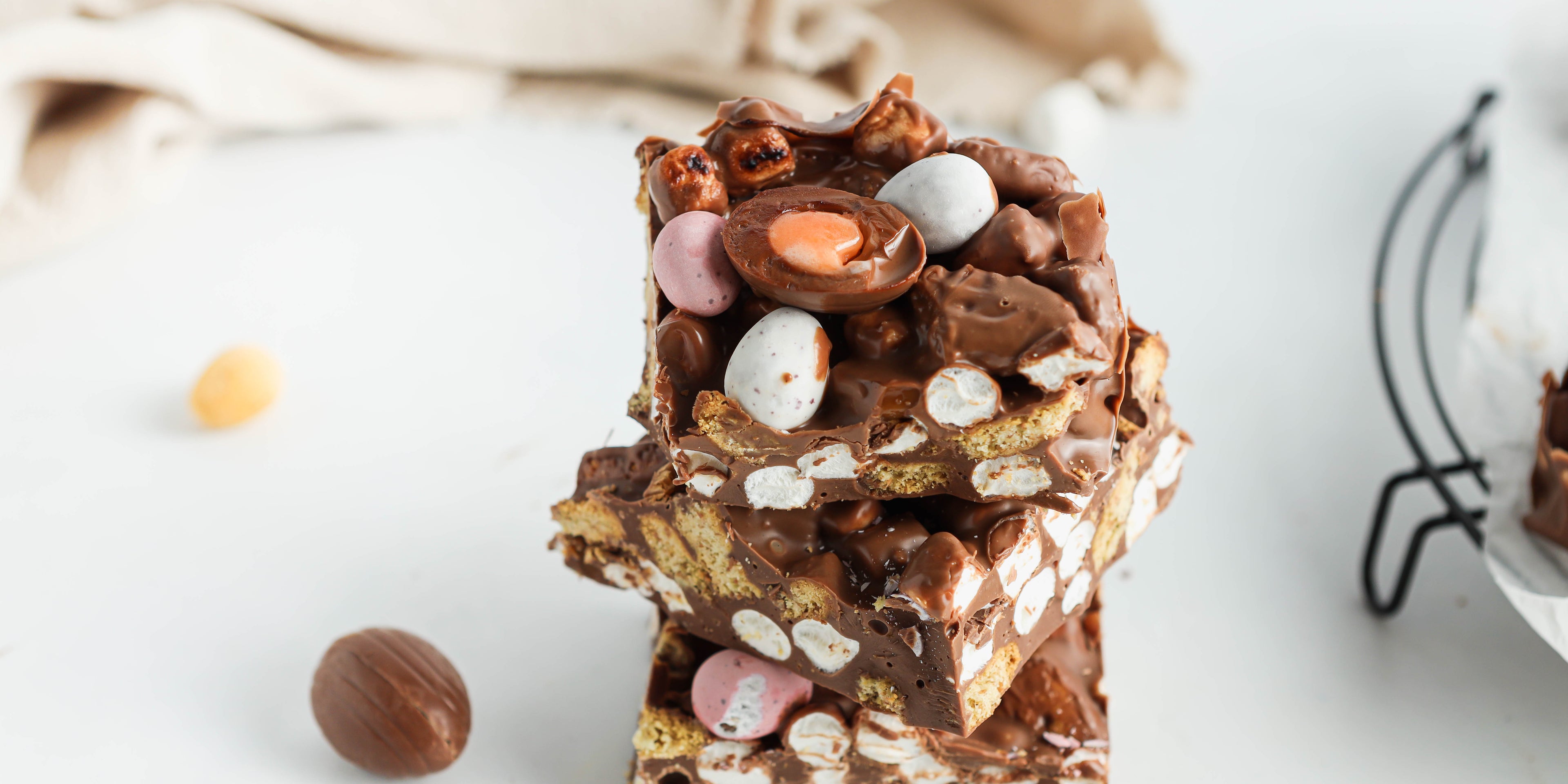 Close up of slices of Easter Egg Rocky Road stacked ontop of each other, filled with mini eggs, creme eggs and marshmallows