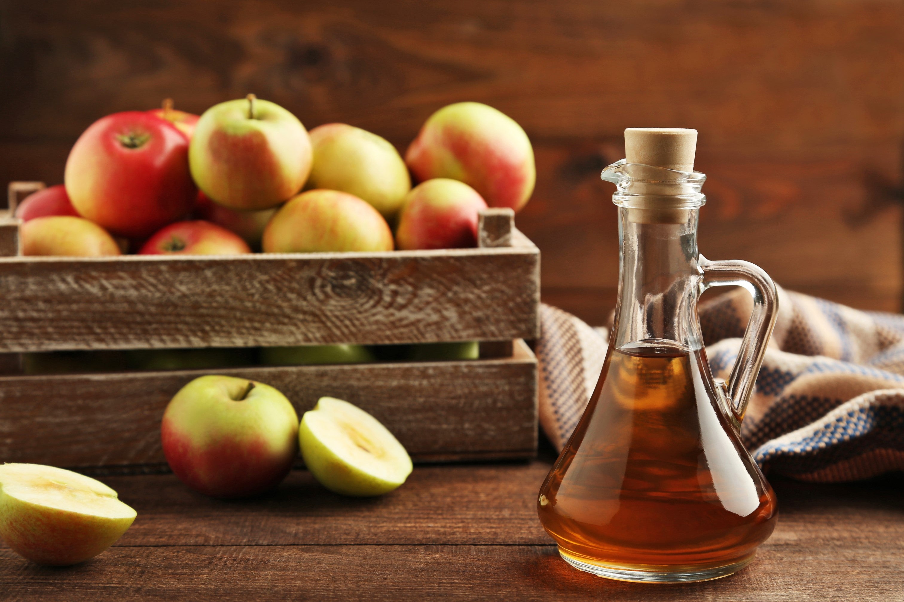 Bottle of apple cider vinegar next to a box of Pink Lady apples