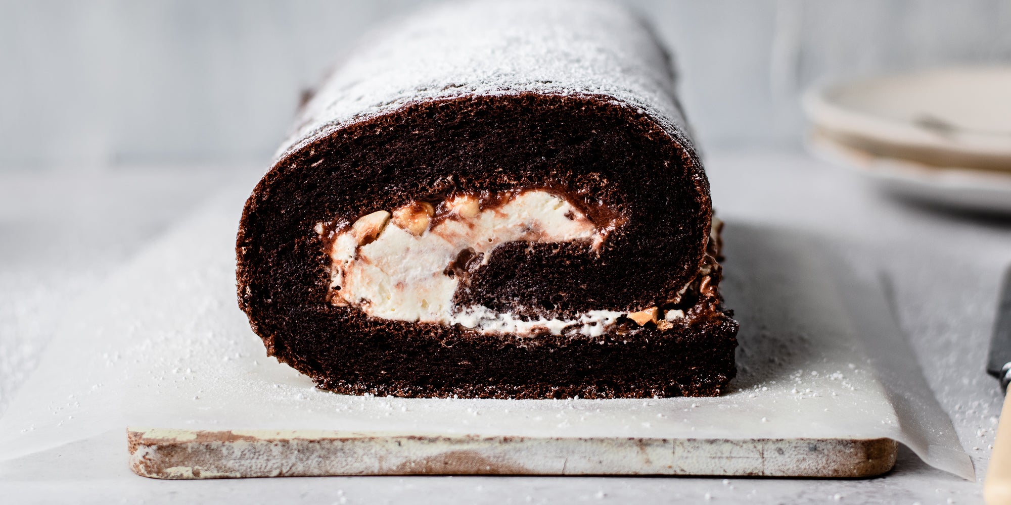 Close up of Chocolate Roulade on a serving board, dusted with Icing Sugar