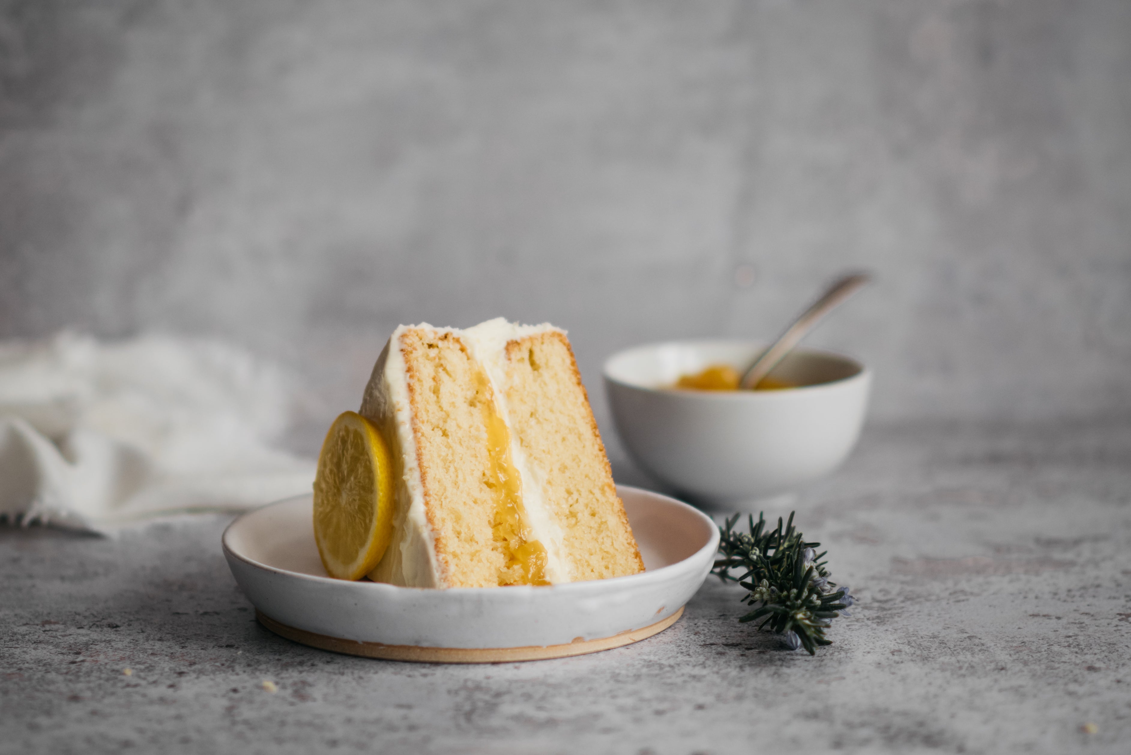 Close up of a slice of Gluten Free Elderflower & Lemon Cake served on a plate, showing the lemon filled centre