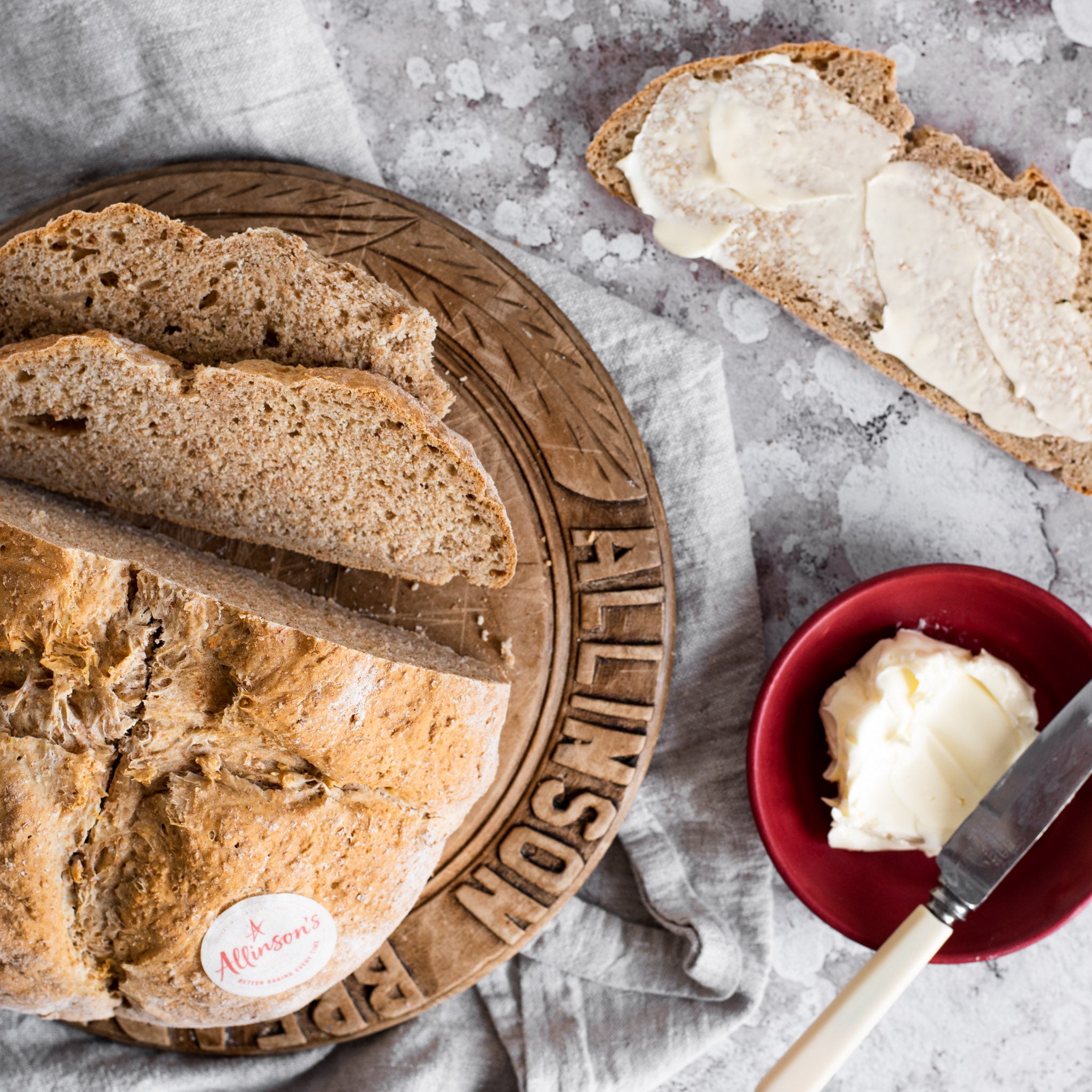 Slices of Soda Bread on a wooden breadboard next to a pot of butter