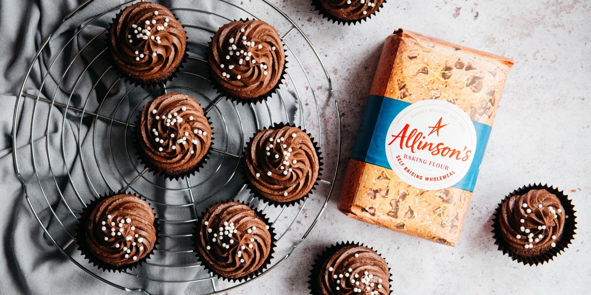 Flat lay Wholemeal Chocolate Cupcakes next to a bag of Allinson's Wholemeal Self Raising flour