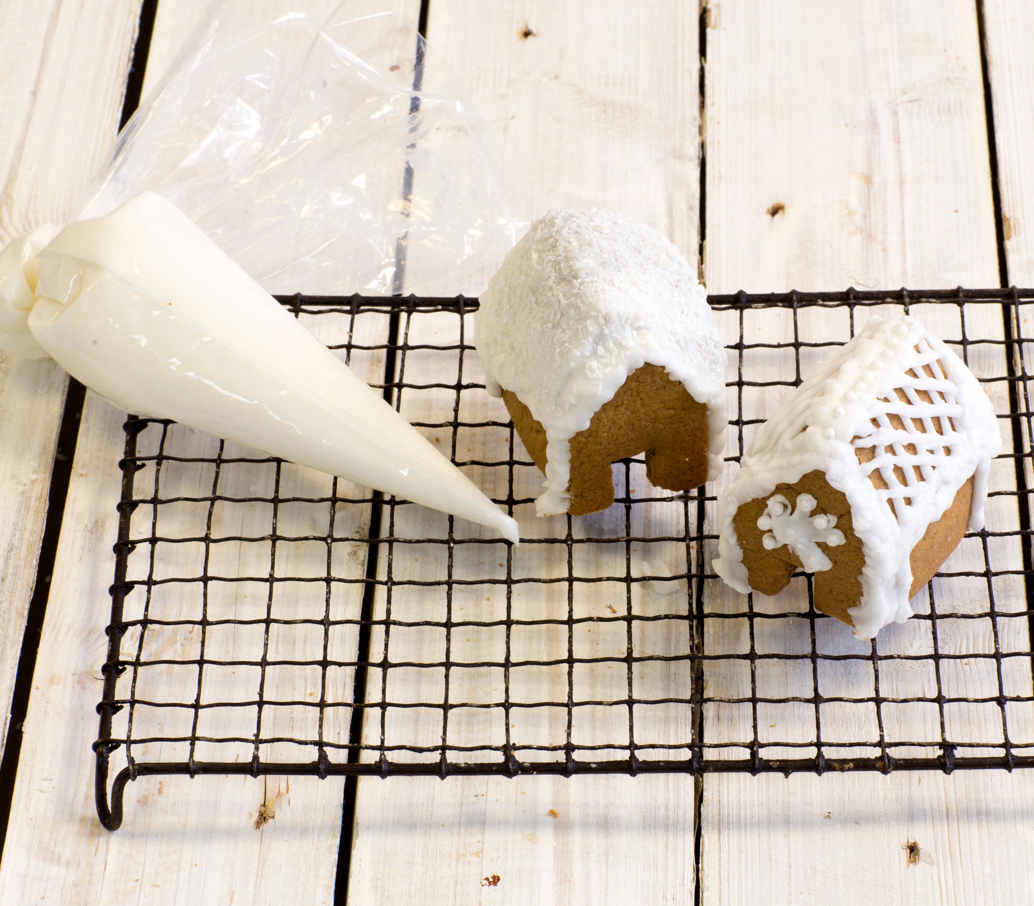 Gingerbread house construction with icing bag on cooling rack