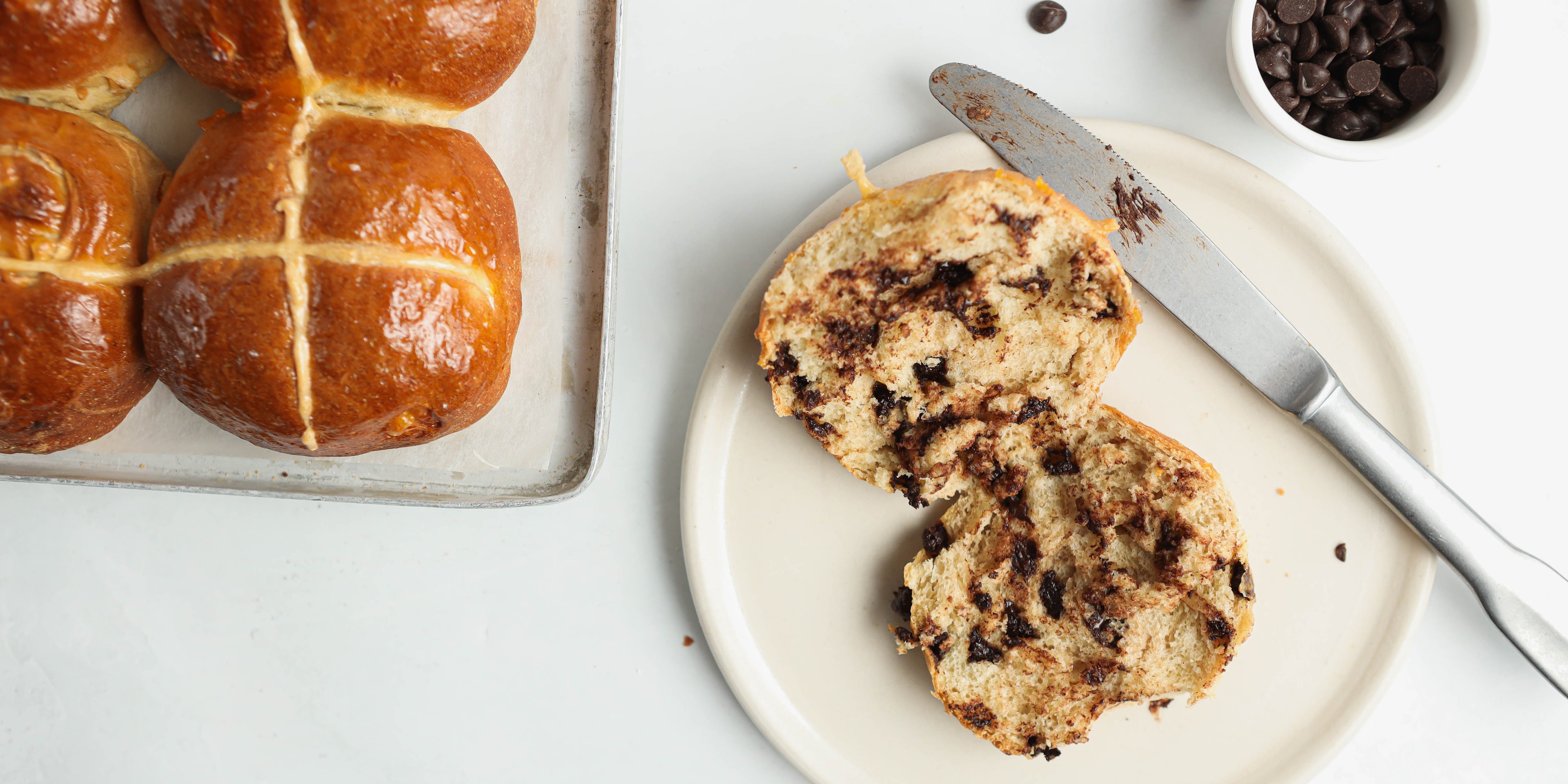 Vegan Hot Cross Buns filled with vegan dark chocolate chips, sliced in half ready to serve