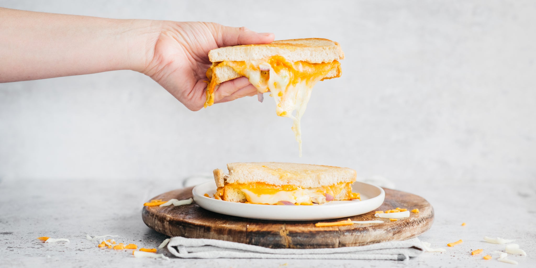 Hand lifting a fried egg and cheese sandwich made with white bread