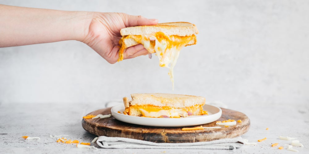 Hand lifting a fried egg and cheese sandwich made with white bread