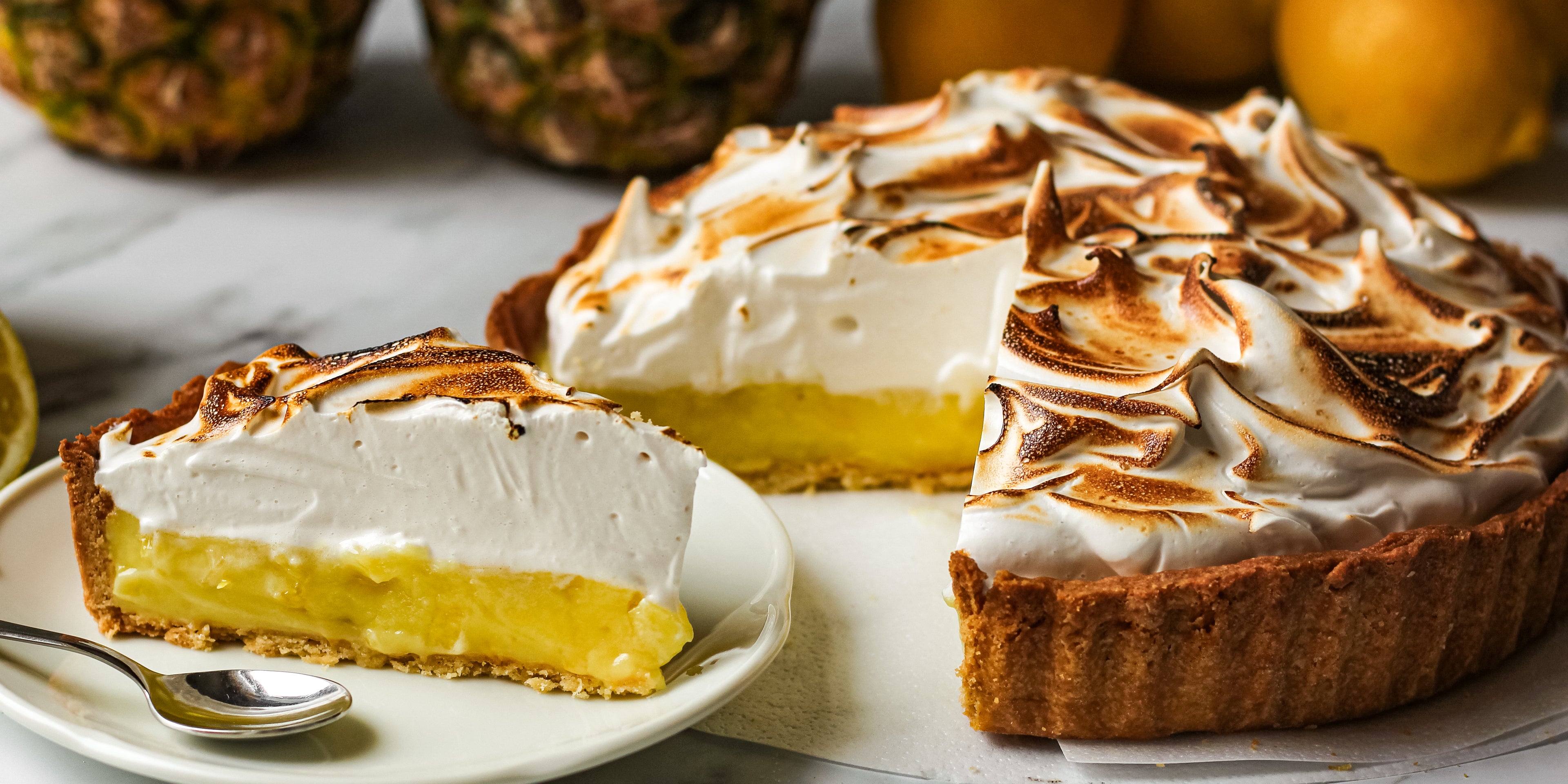 Close up of Vegan Pineapple Meringue Pie with a slice cut out of it showing the yellow pineapple layer and crisp burnt meringue top