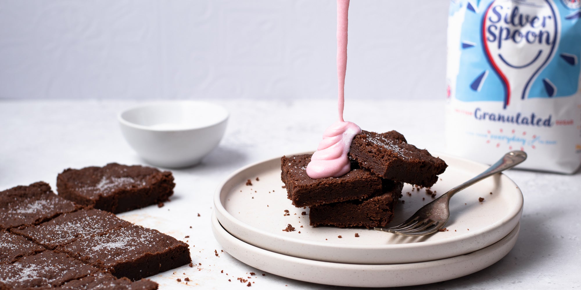 Chocolate Concrete Cake drizzled with pink custard on a stack of plates