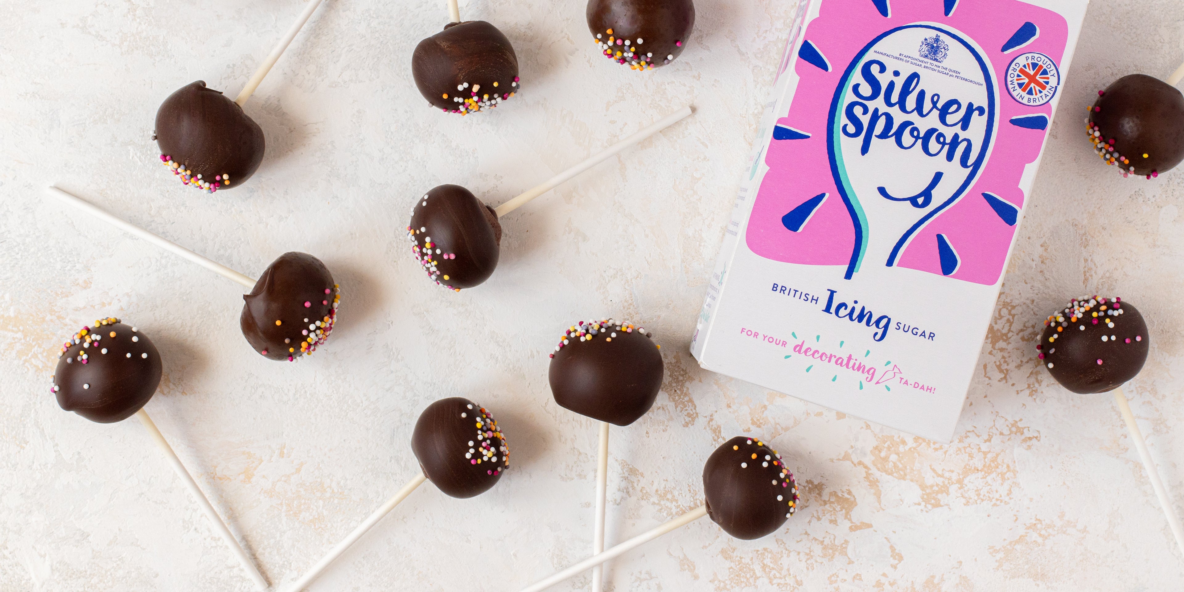 Top view of Chocolate Cake Pops scattered around a box of Silver Spoon Icing sugar