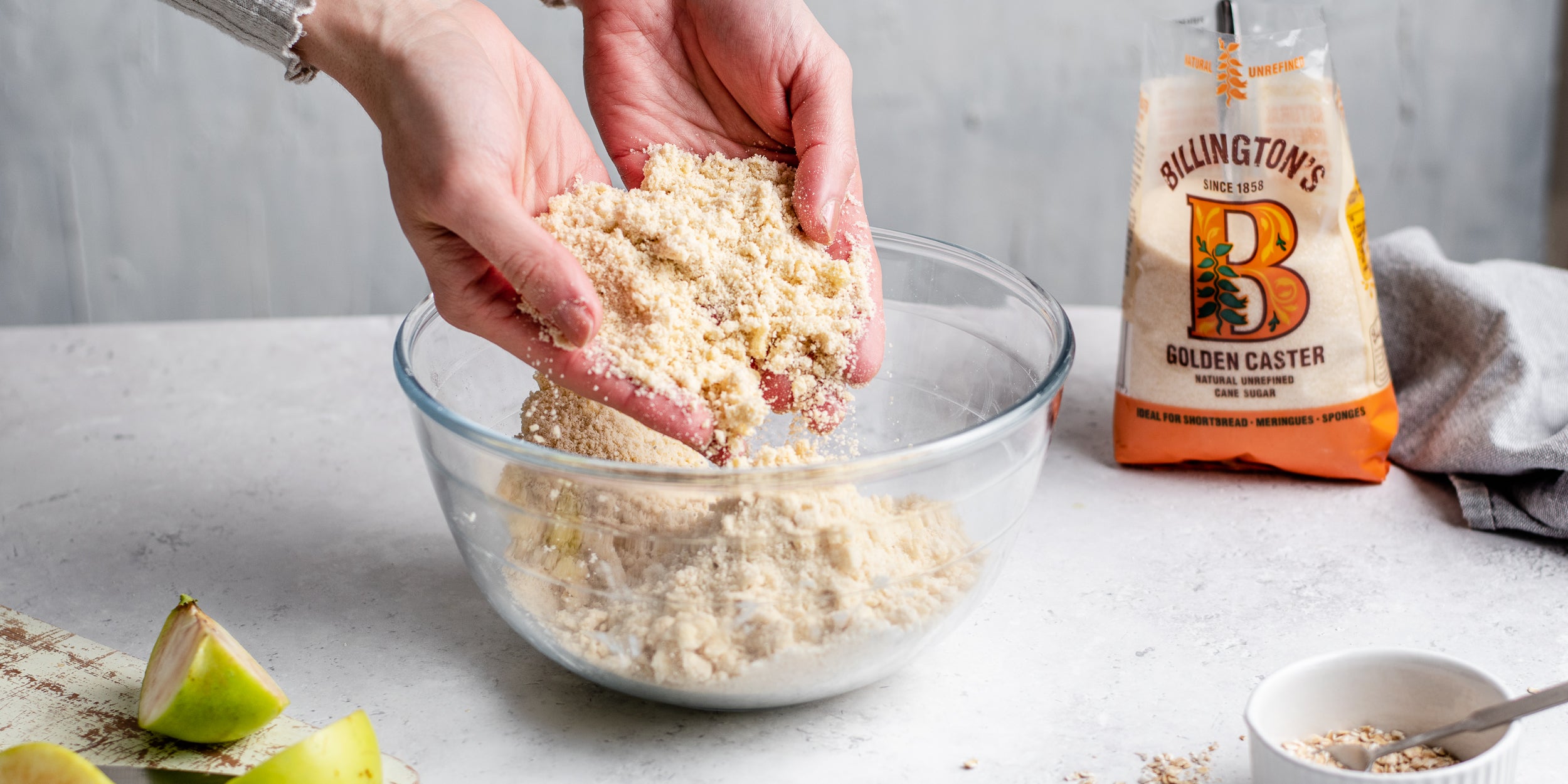Hands combining the crumble mixture together with Billington's Golden Caster Sugar ready to bake in the oven