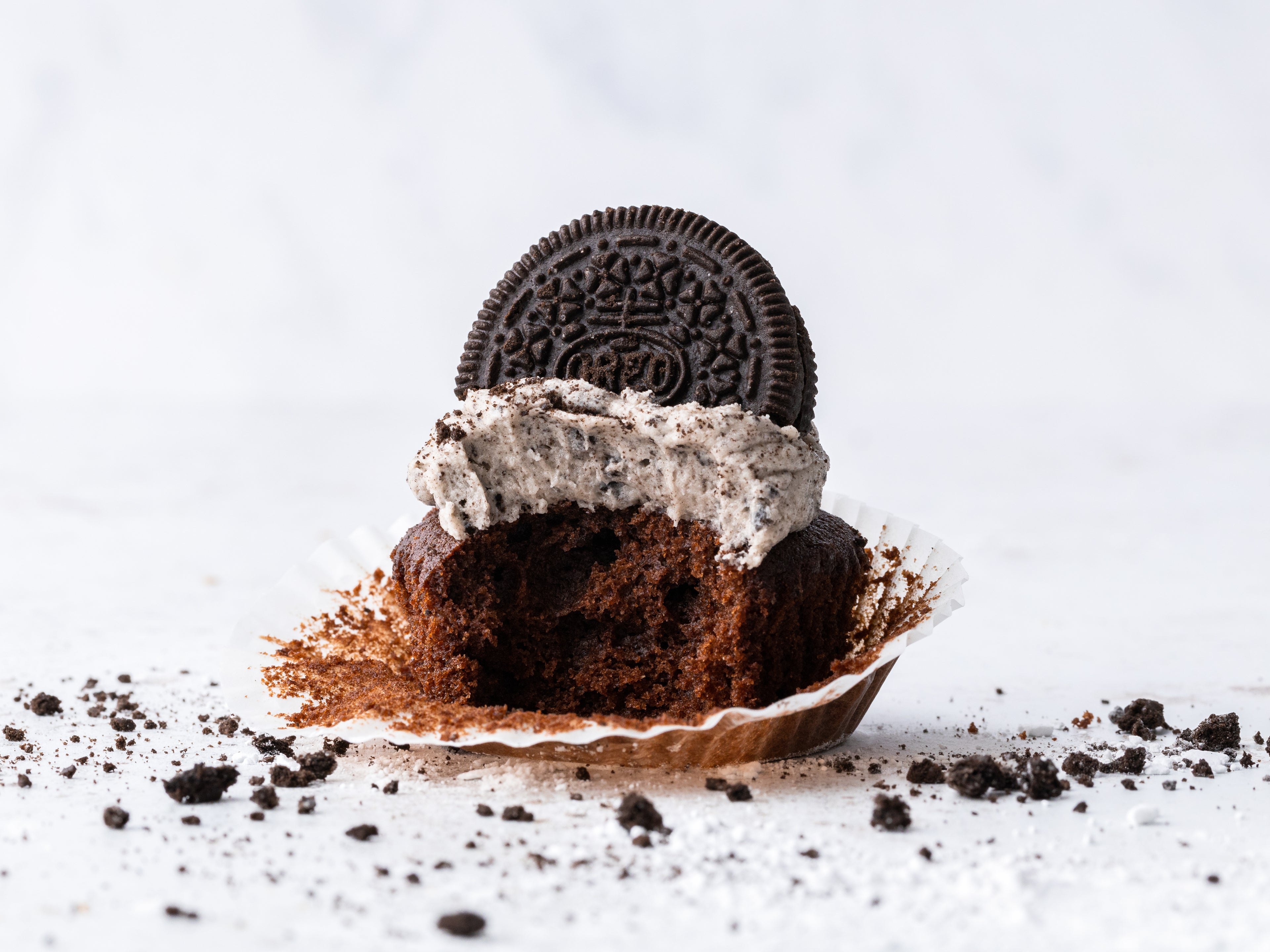 Oreo cupcake with the wrapper peeled back and bite taken out of it
