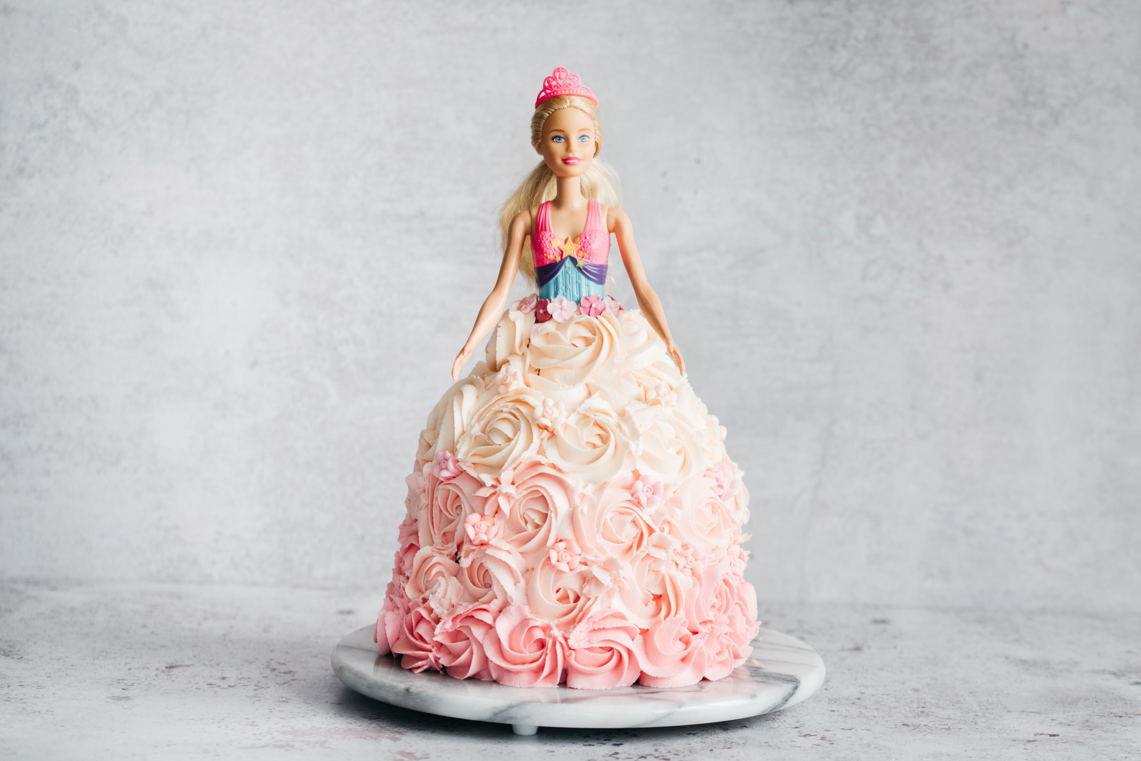 Princess Barbie Cake decorated with pink and white swirls ready to serve