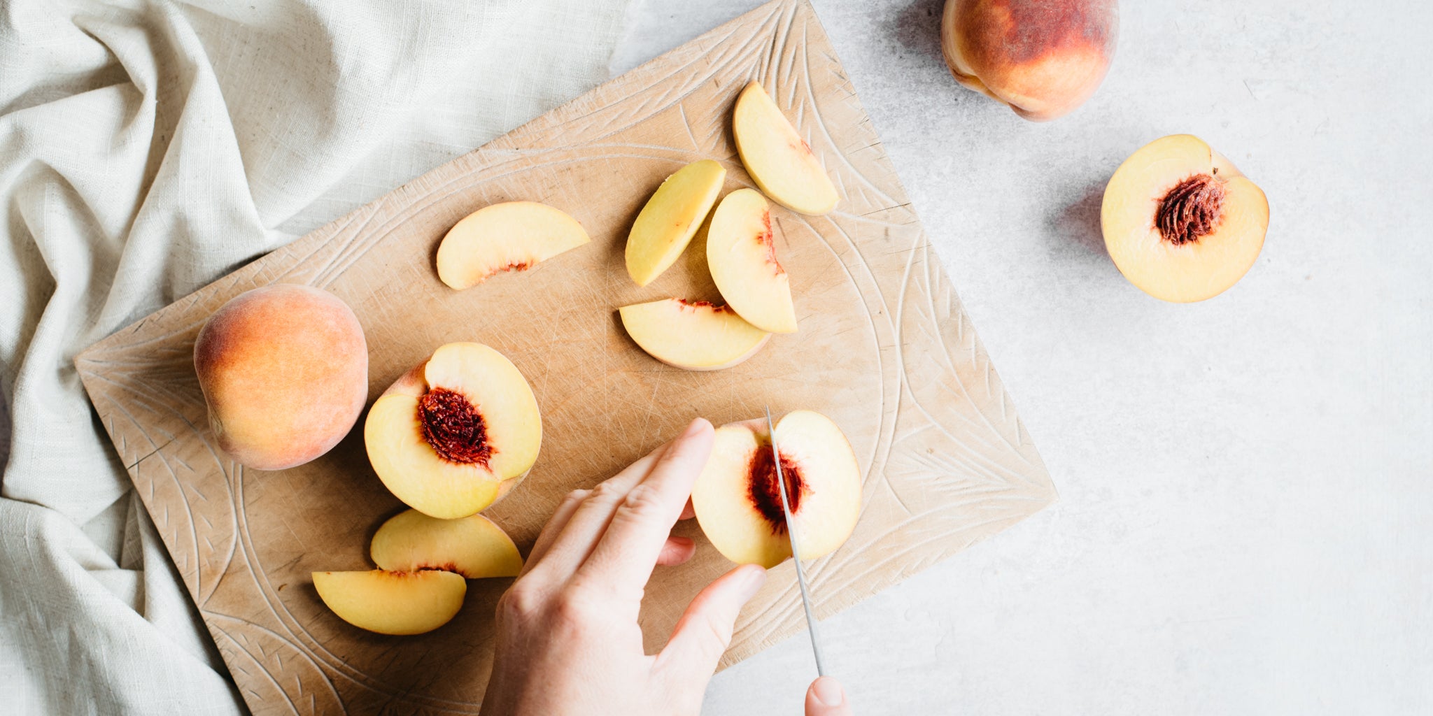 Peaches being chopped on a wooden chopping board
