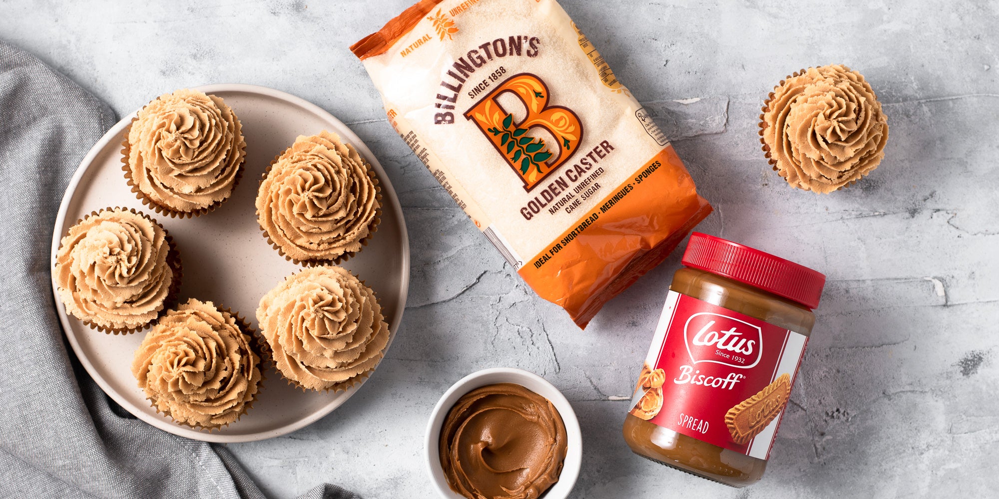 birds eye view of biscoff cupcakes next to Lotus Biscoff Spread and bag of sugar