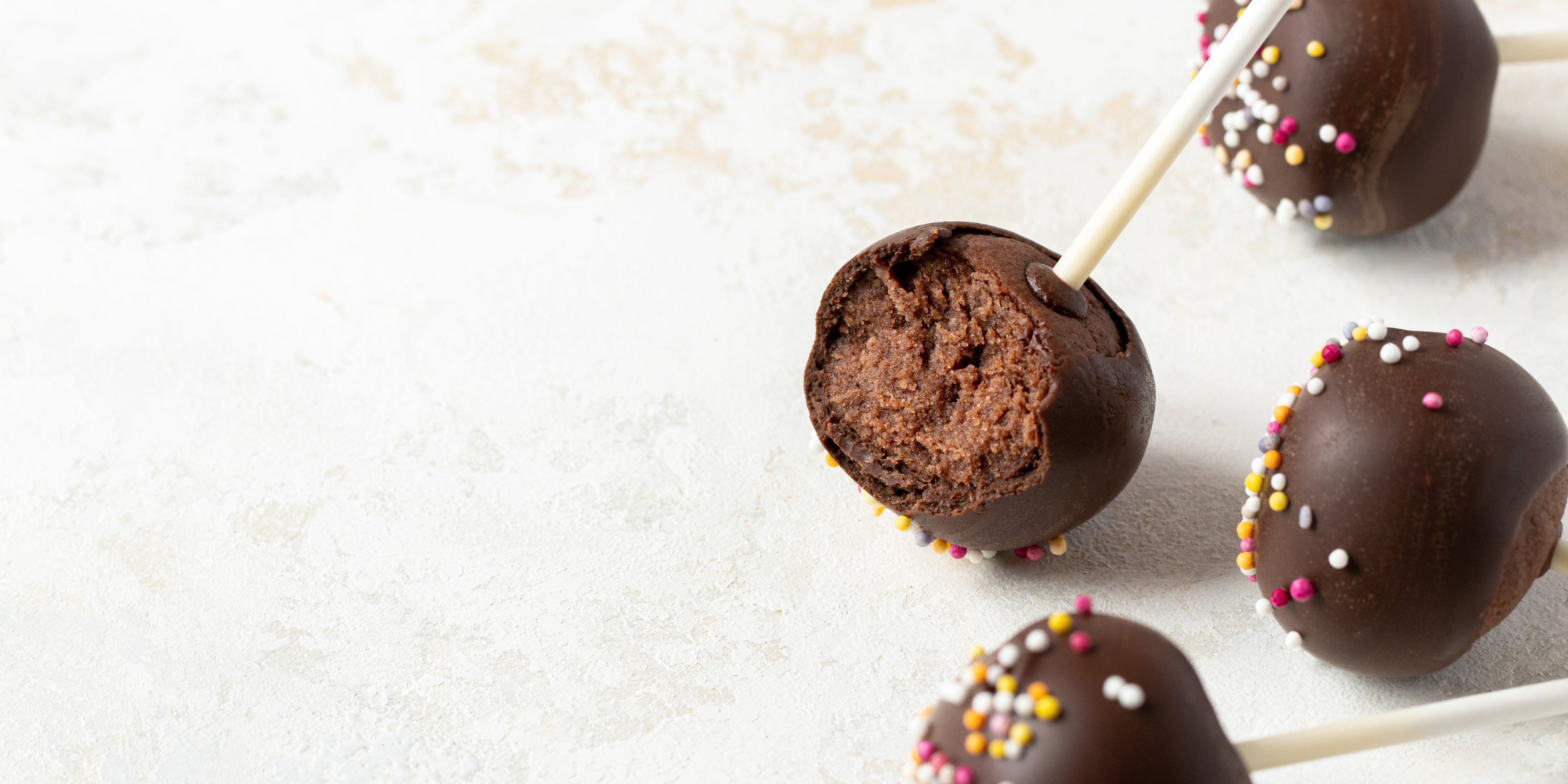 Close up of a Chocolate Cake Pop with a bite taken out of it, showing the chocolate cake centre and chocolate icing coating