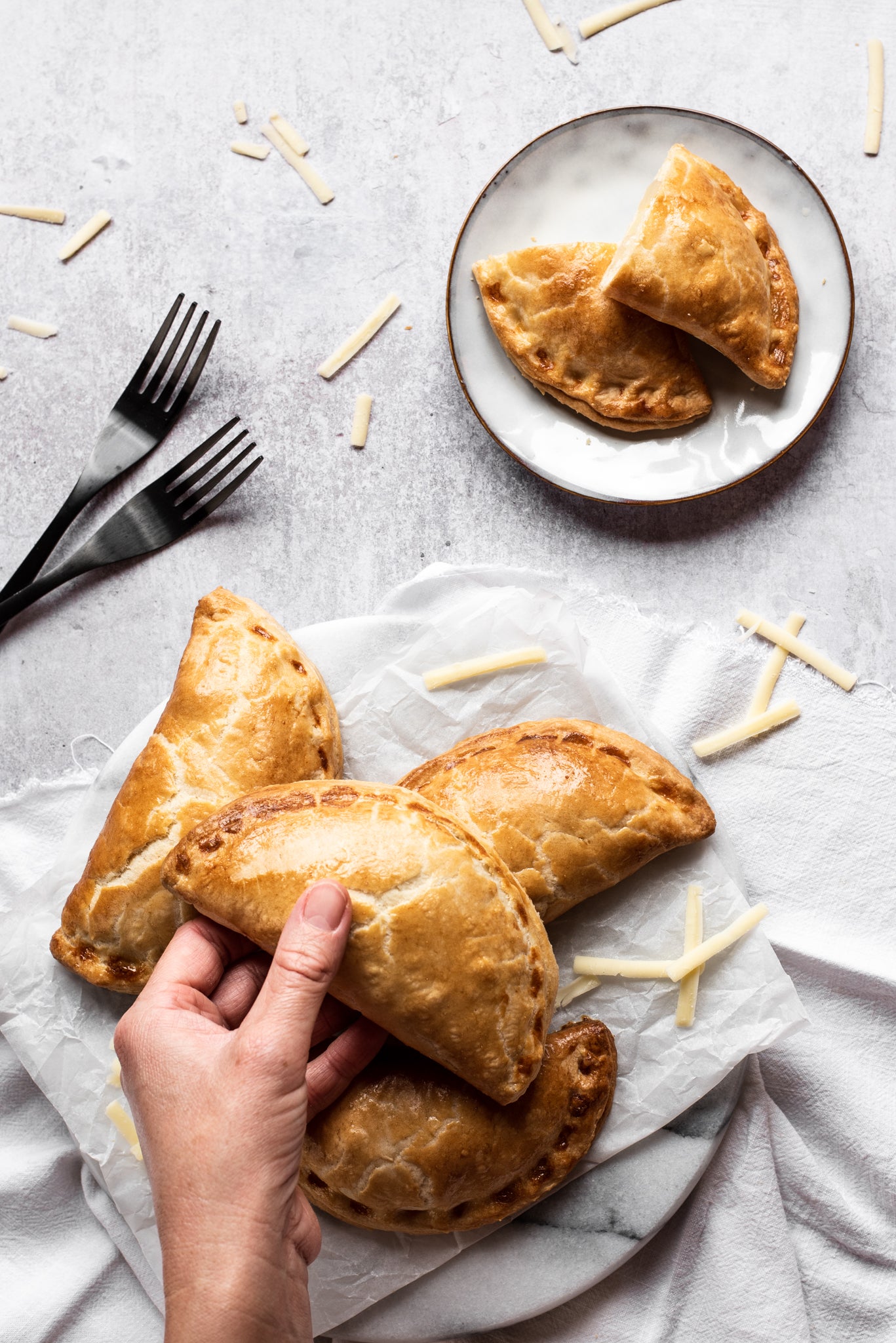 Pile of pasties, hand holding one, one sliced open in background