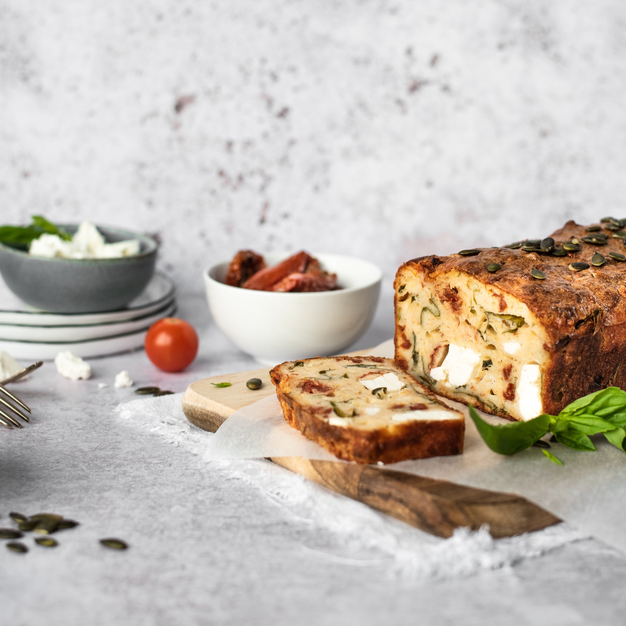 Feta and tomato loaf with slice removed on a chopping board