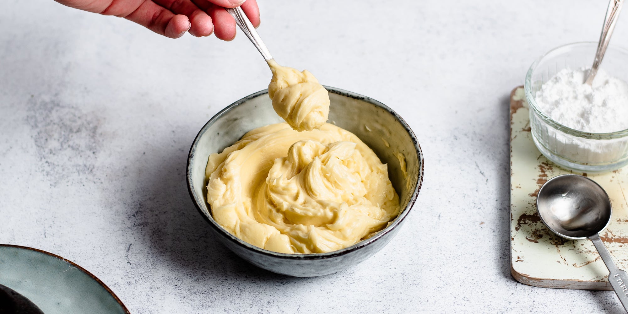 Bowl of Brandy Butter with a hand holding a spoon dipping in to take a dollop
