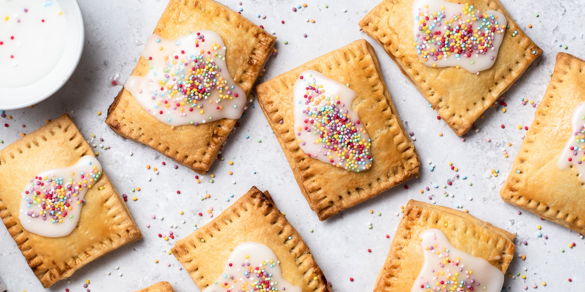 Homemade Pop Tarts with icing and sprinkles. Sprinkles scattered