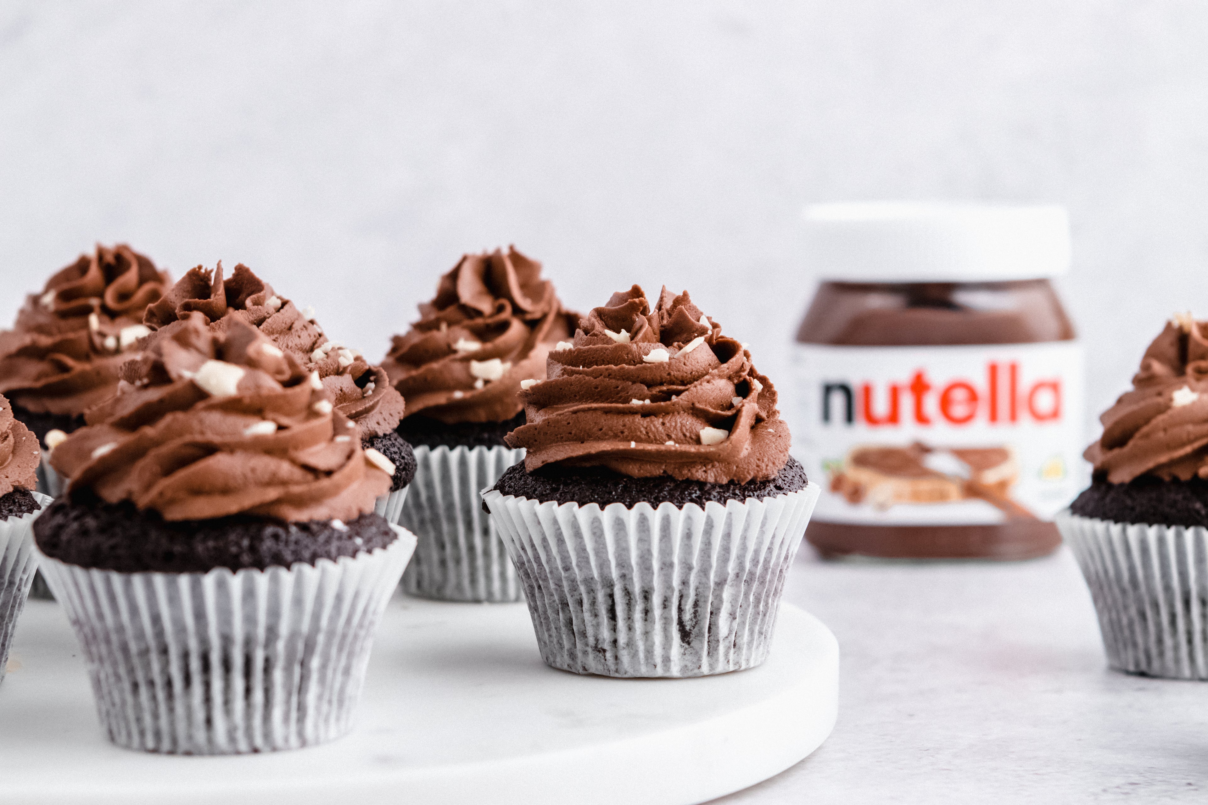 Nutella cupcakes on a marble tray, with a jar of Nutella in the background