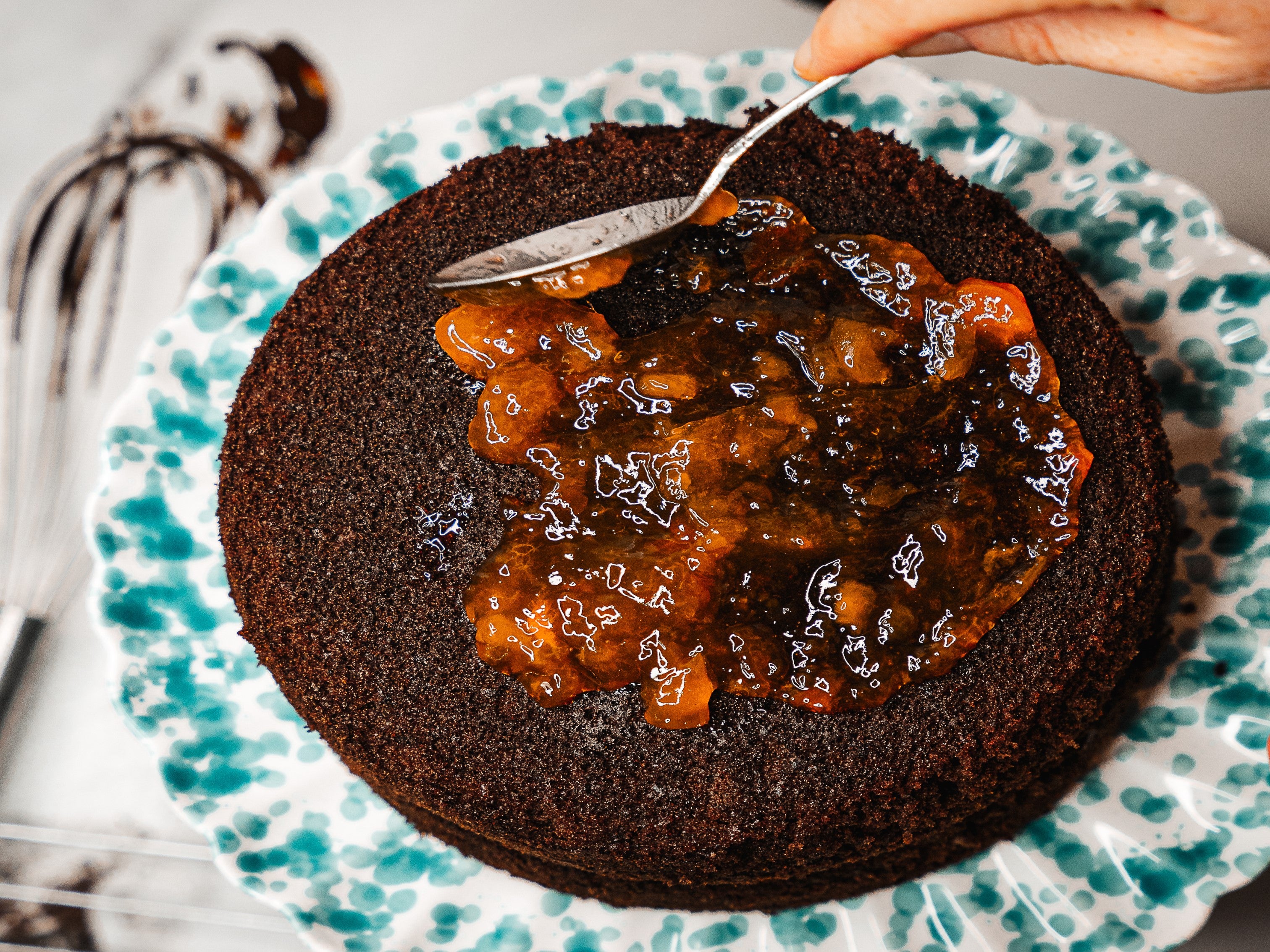 Spreading apricot jam over the middle layer of Mary Berry's chocolate cake