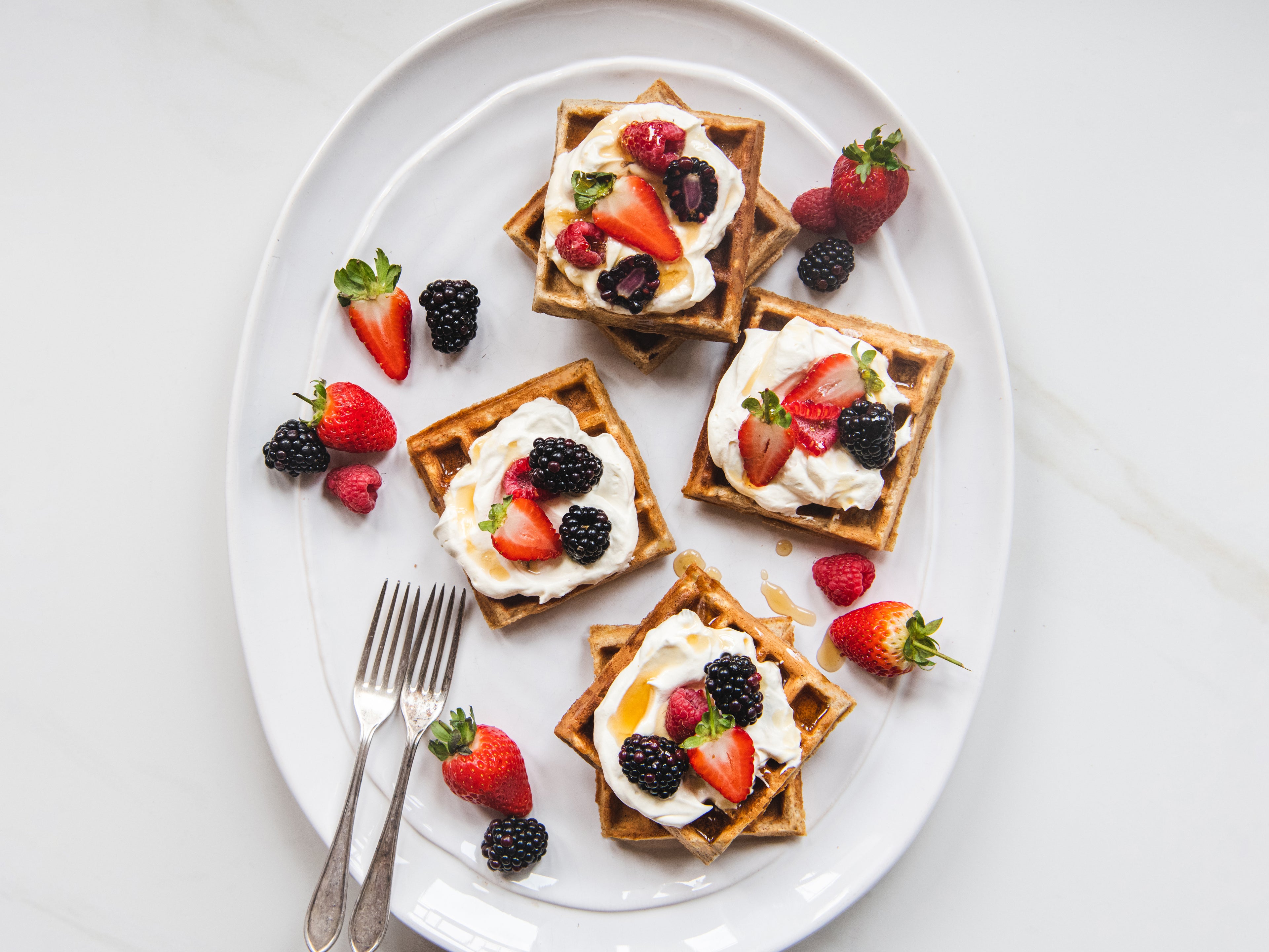 Top view of Banana waffles topped with whipped cream, and seasonal berries