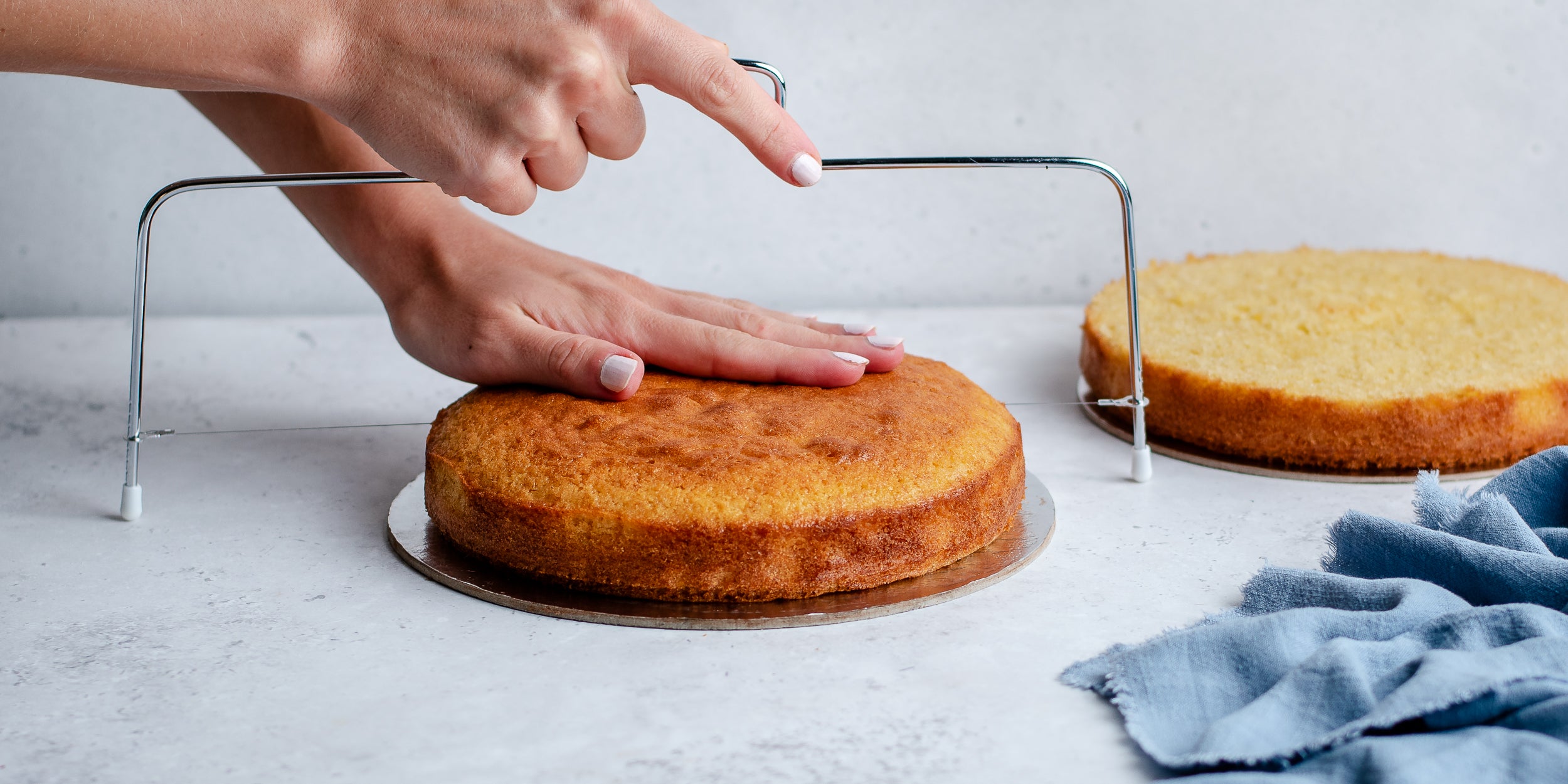 Madeira sponge with hand slicing the top of the cake off