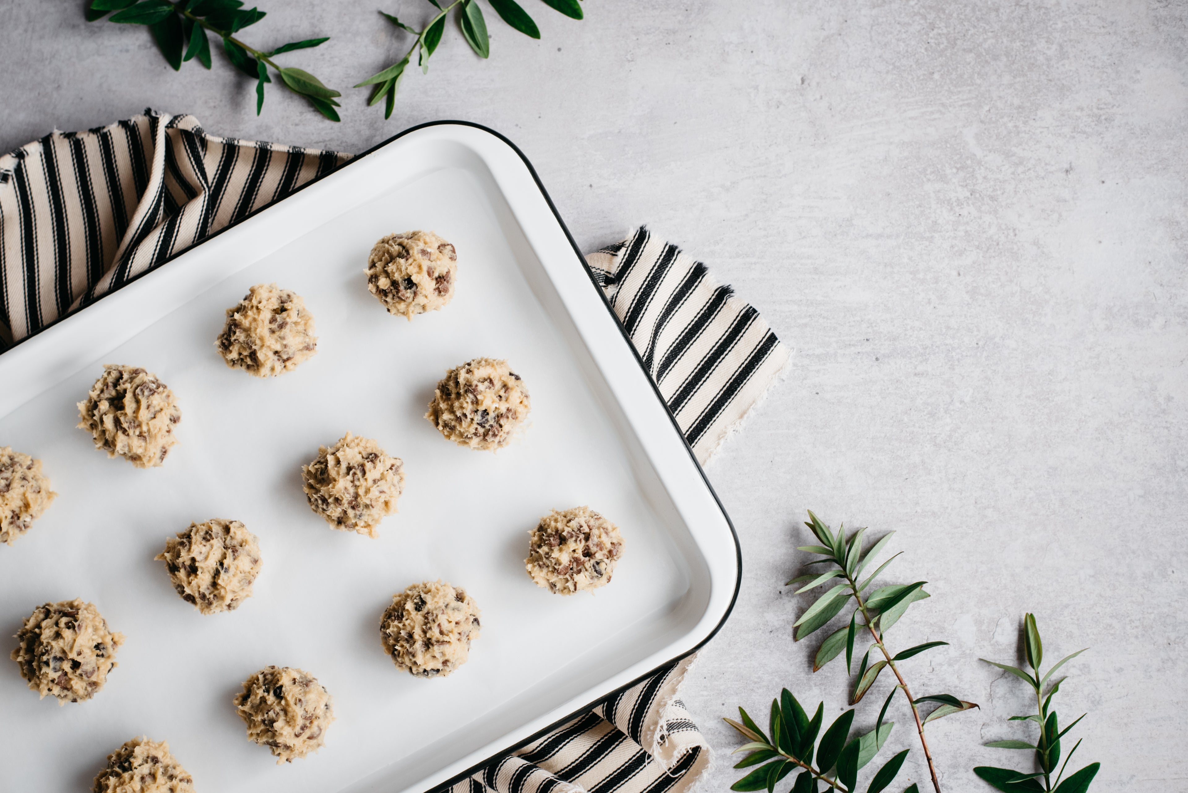 Low sugar chocolate chip cookie dough rolled into balls on a baking sheet