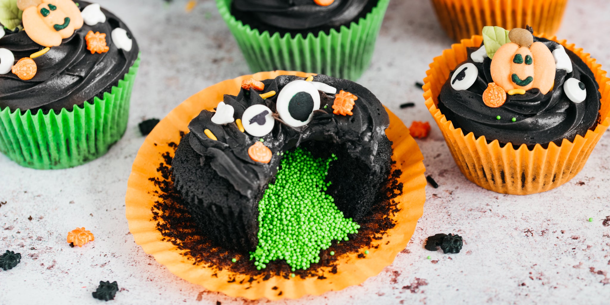 Halloween cupcakes with black icing and green sprinkle centre