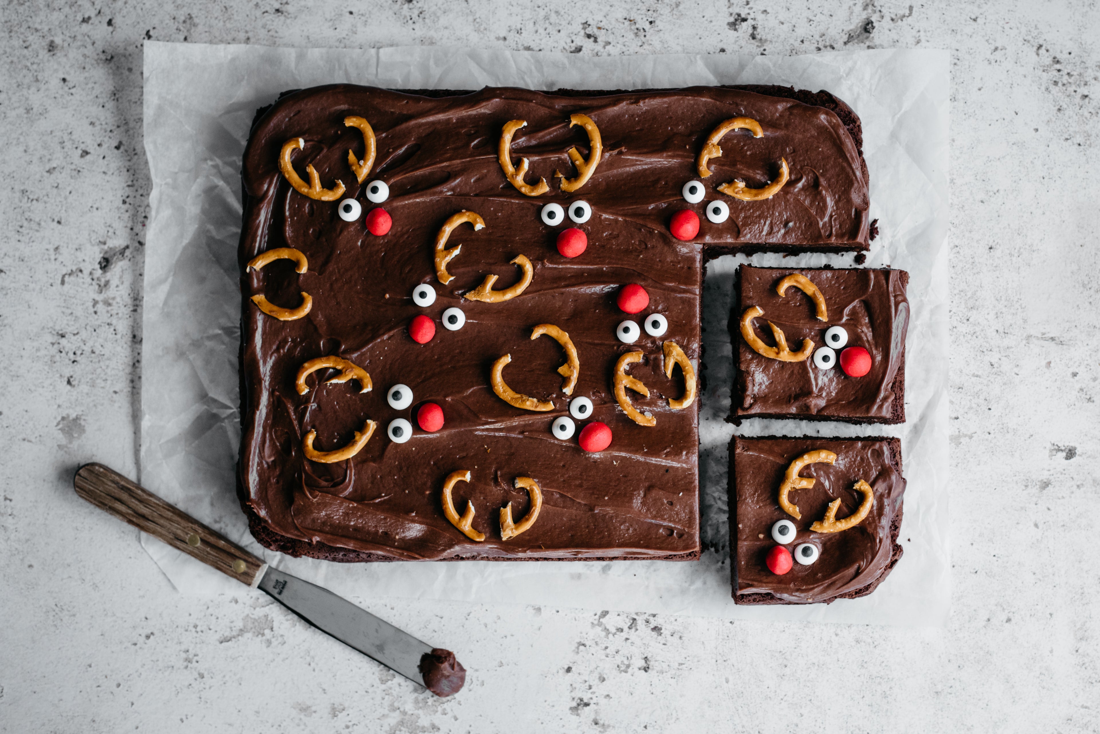 Chocolate & Caramel Reindeer Traybake with slices cut out next to a spoon covered in chocolate frosting
